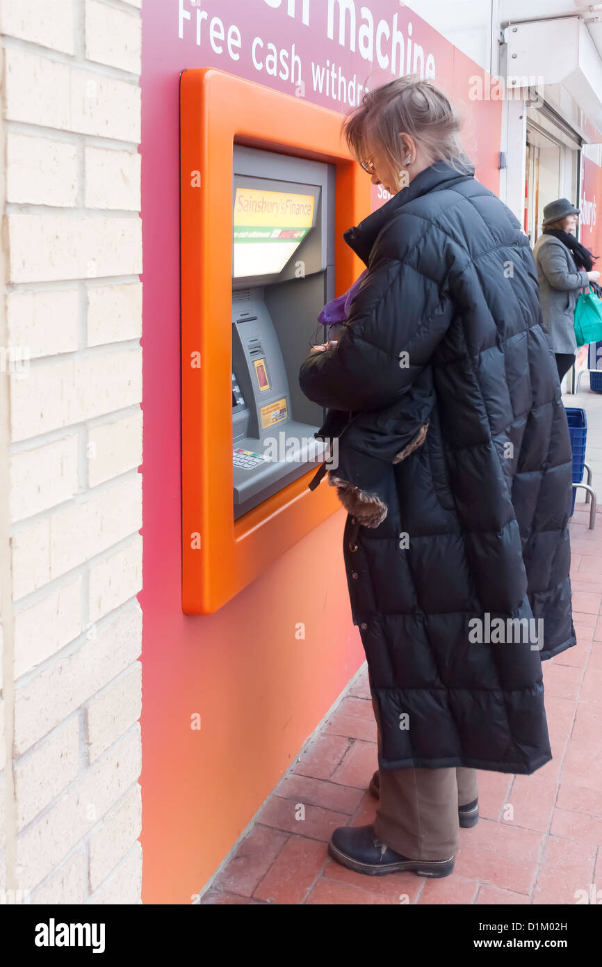 A woman withdrawing cash from a Sainsbury's ATM or Cash Machine Stock Photo