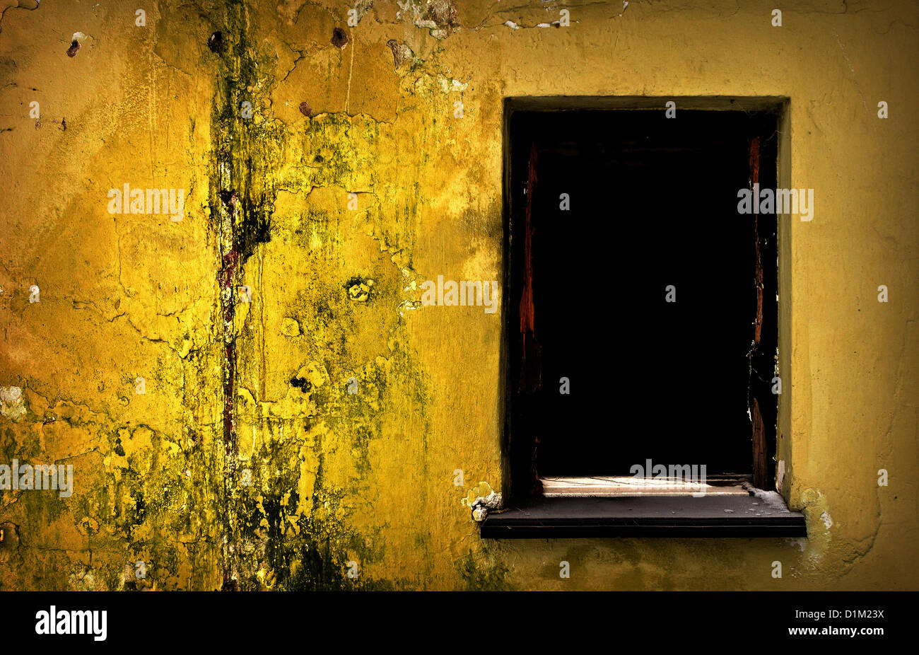 Black window of abandoned ruined building and golden-yellow wall. Stock Photo