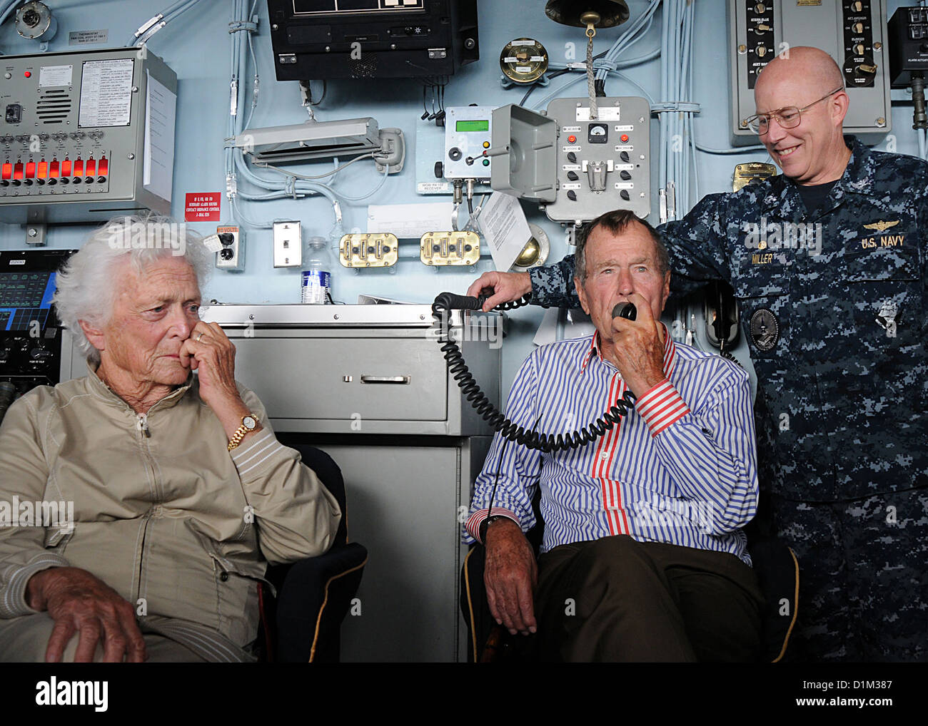 Former President George H. W. Bush, center, addresses U.S. Sailors using the public address system during a visit to the aircraft carrier USS George H. W. Bush (CVN 77) in the Atlantic Ocean Jan. 14, 2010. Accompanying Bush are wife Barbara Bush, left, an Stock Photo
