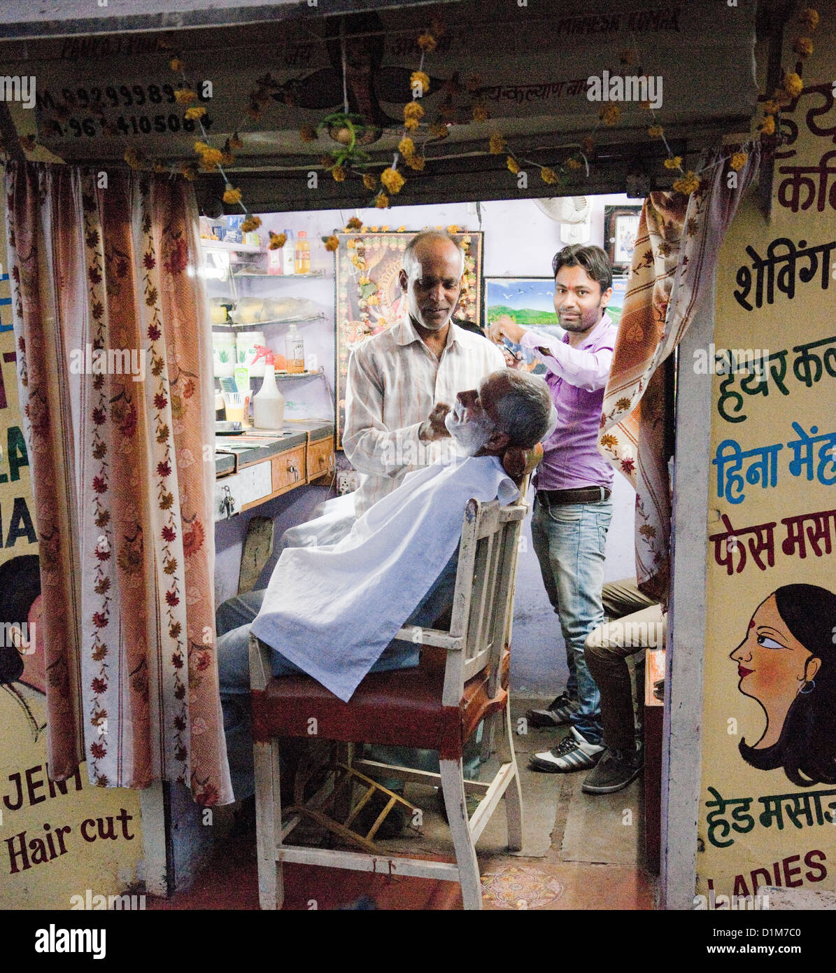A barber shaves a customer in a barbers shop with soap and water and cut throat razer in Udaipur Rajasthan india Stock Photo