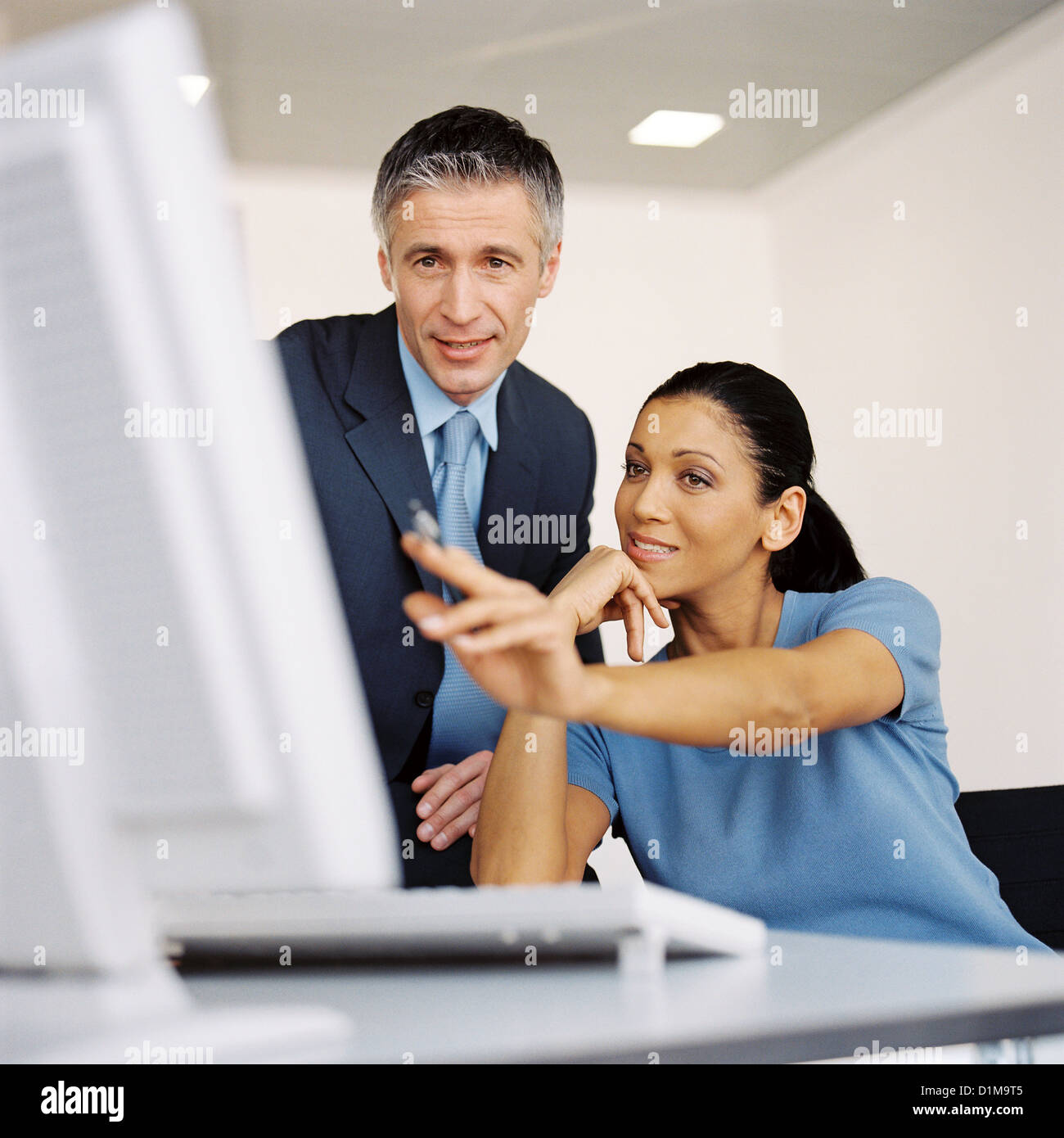 Businessman and businesswoman in office looking at computer smiling License free except ads and billboards Stock Photo