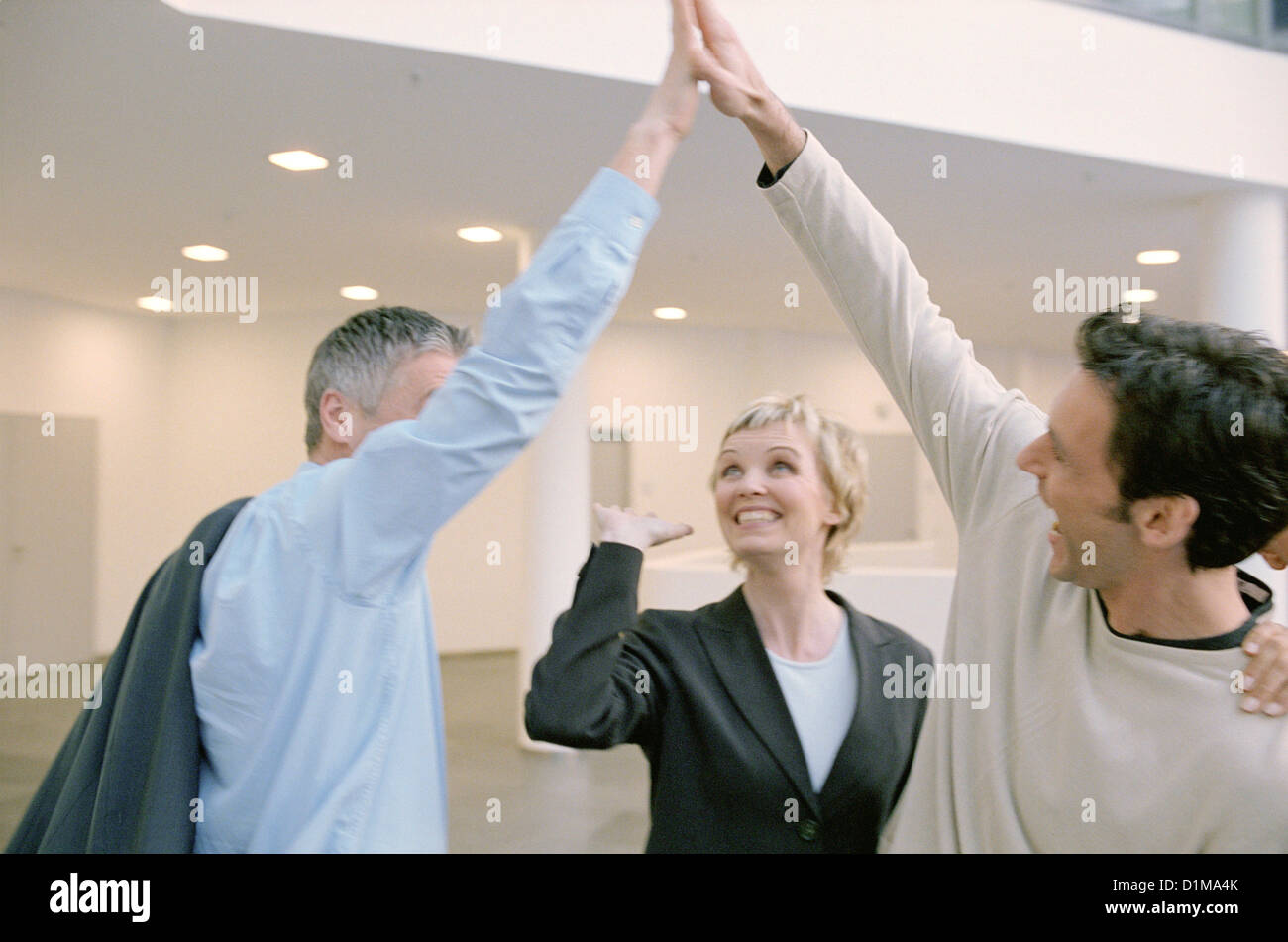 Three business people to give so a high five License free except ads and billboards Stock Photo