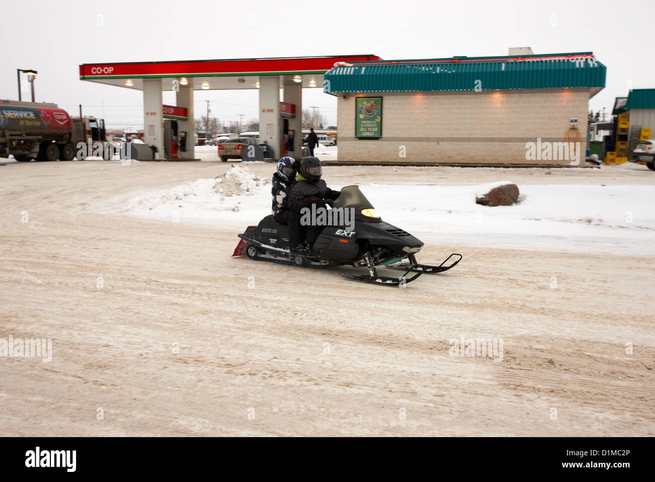 couple on a snowmobile leaving a gas station Kamsack Saskatchewan Canada Stock Photo