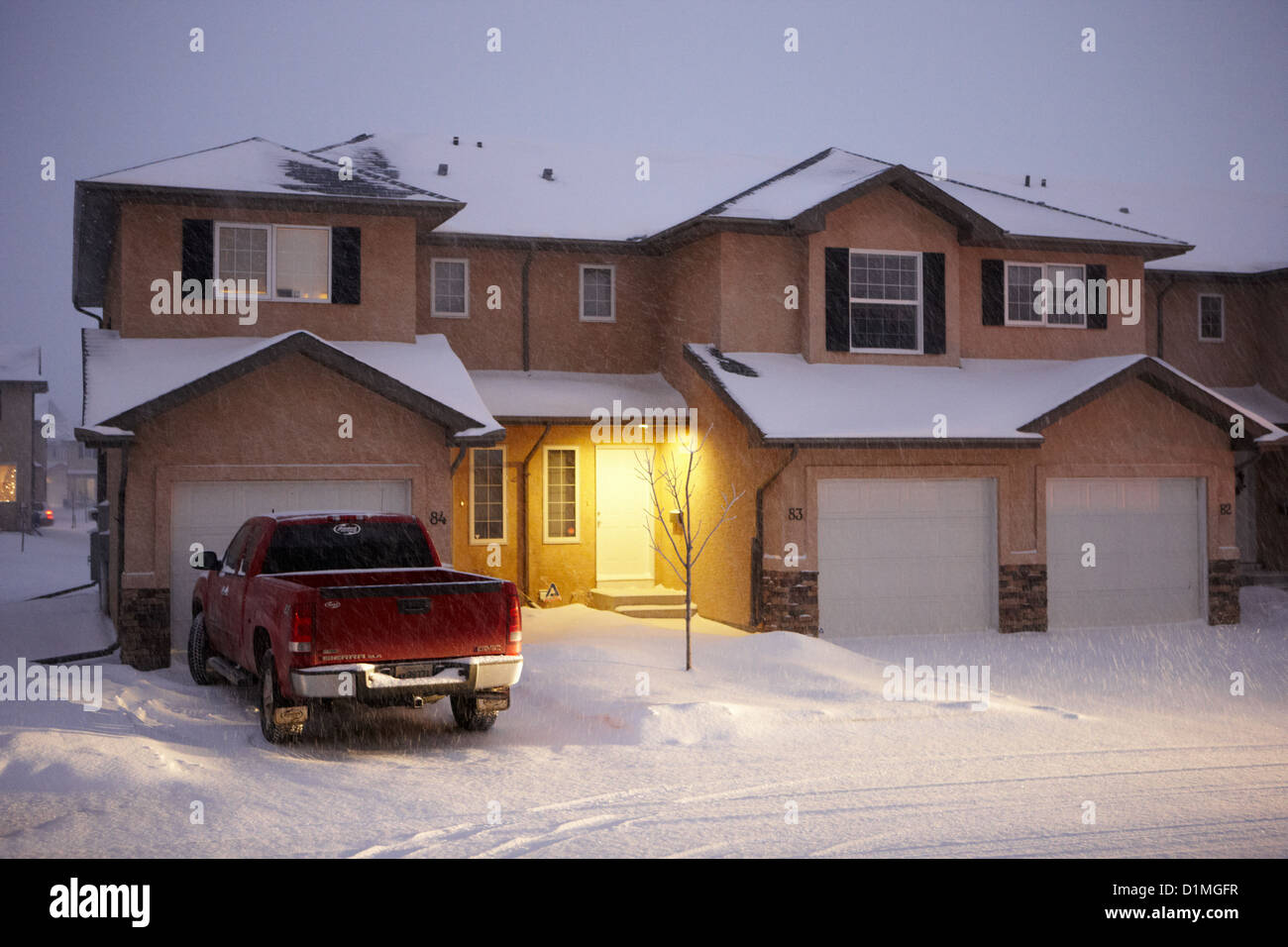 truck parked outside house with snow falling in residential neighborhood in Saskatoon Saskatchewan Canada Stock Photo