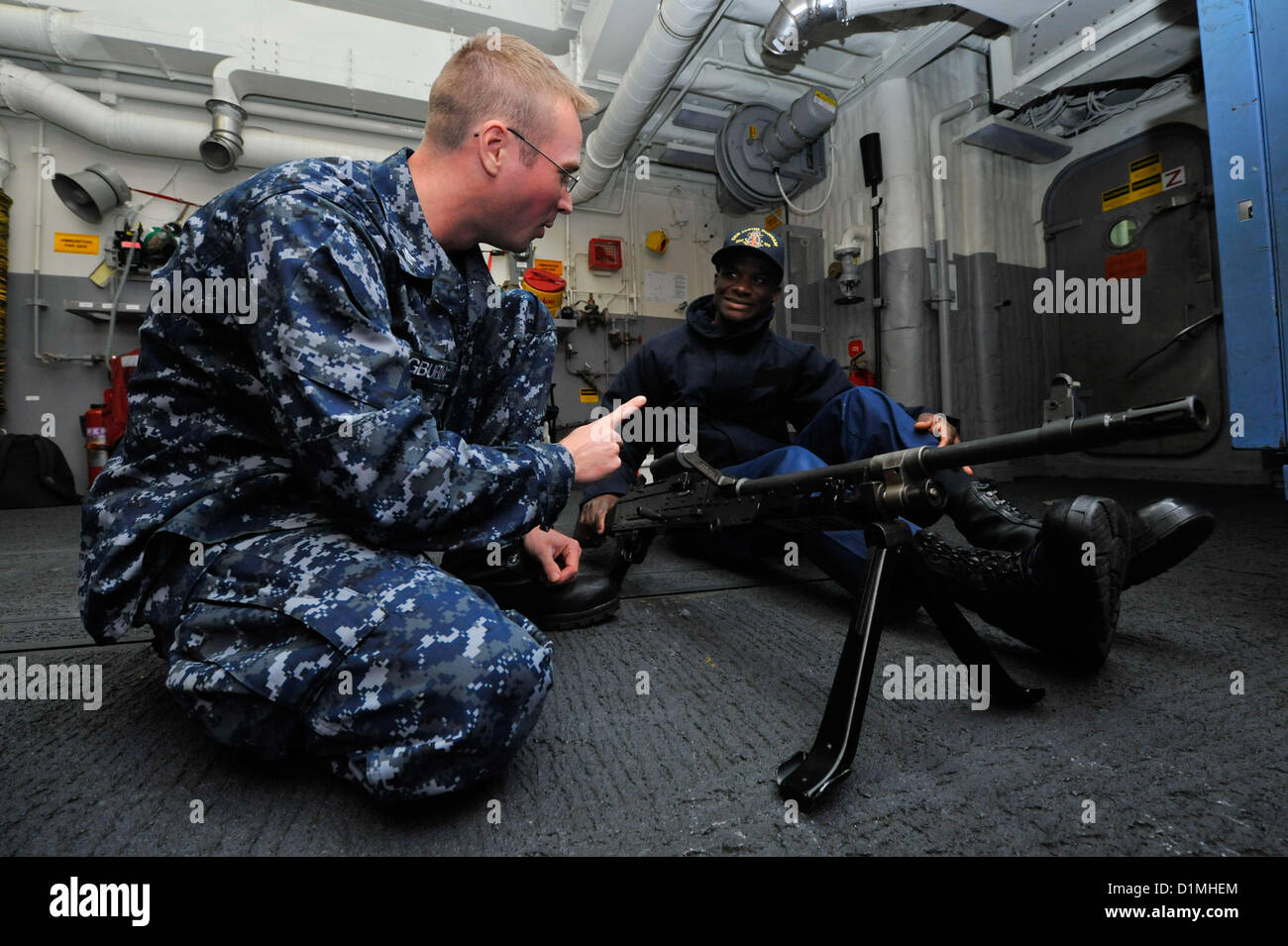 Gunner’s Mate 2nd Class Daniel Pangburn, left, instructs Ship’s Serviceman 3rd Class Komla Sapey in the proper operation of an M240B machine gun during weapons familiarization aboard the guided-missile destroyer USS Jason Dunham (DDG 109). Jason Dunham is deployed with the John C. Stennis Strike Group to the U.S. 5th Fleet area of responsibility conducting maritime security operations, theater security cooperation efforts and support missions for Operation Enduring Freedom..ARABIAN SEA (Dec.29, 2012)US Navy Photo Stock Photo
