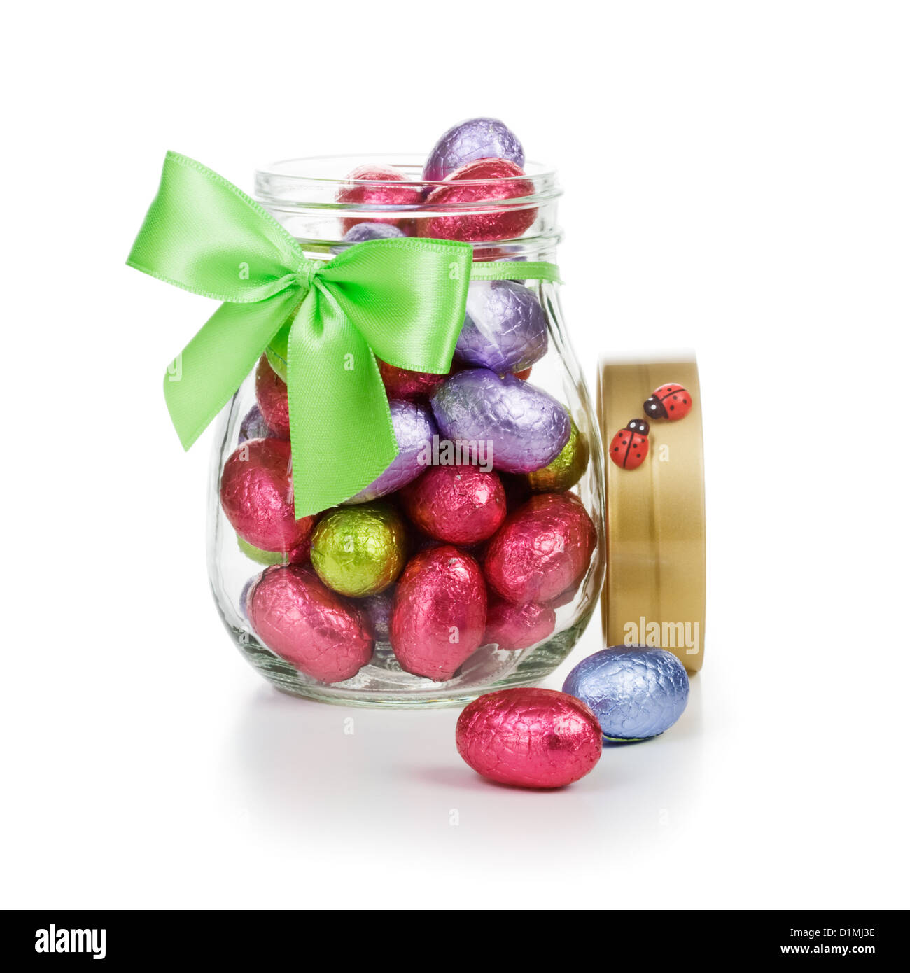 Open glass jar full of chocolate candy Easter eggs wrapped in foil