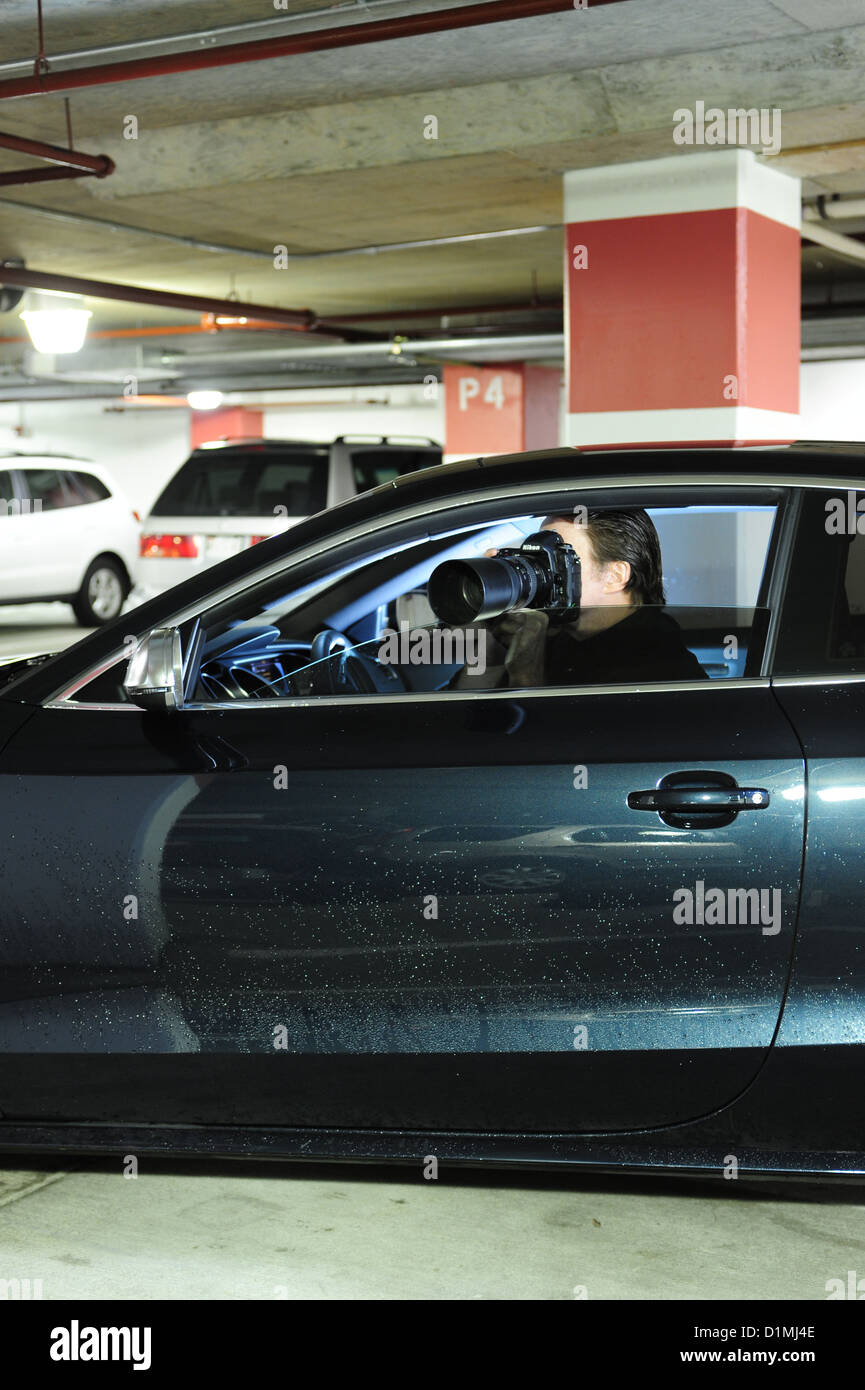 Private eye or private detective investigator in car with camera following someone secretly Stock Photo