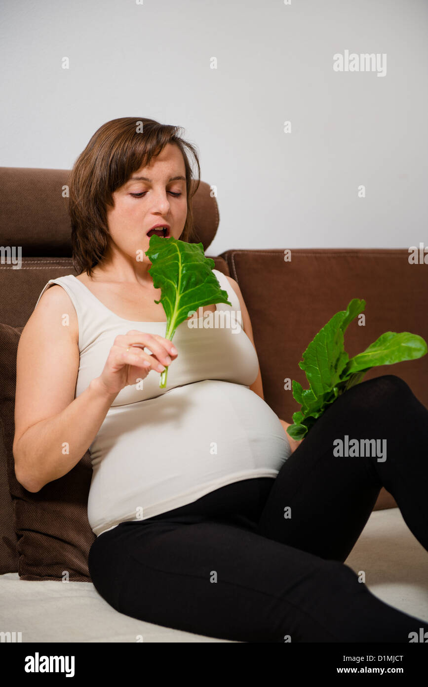 Lifestyle portrait of pregnant woman eating spinach at home Stock Photo