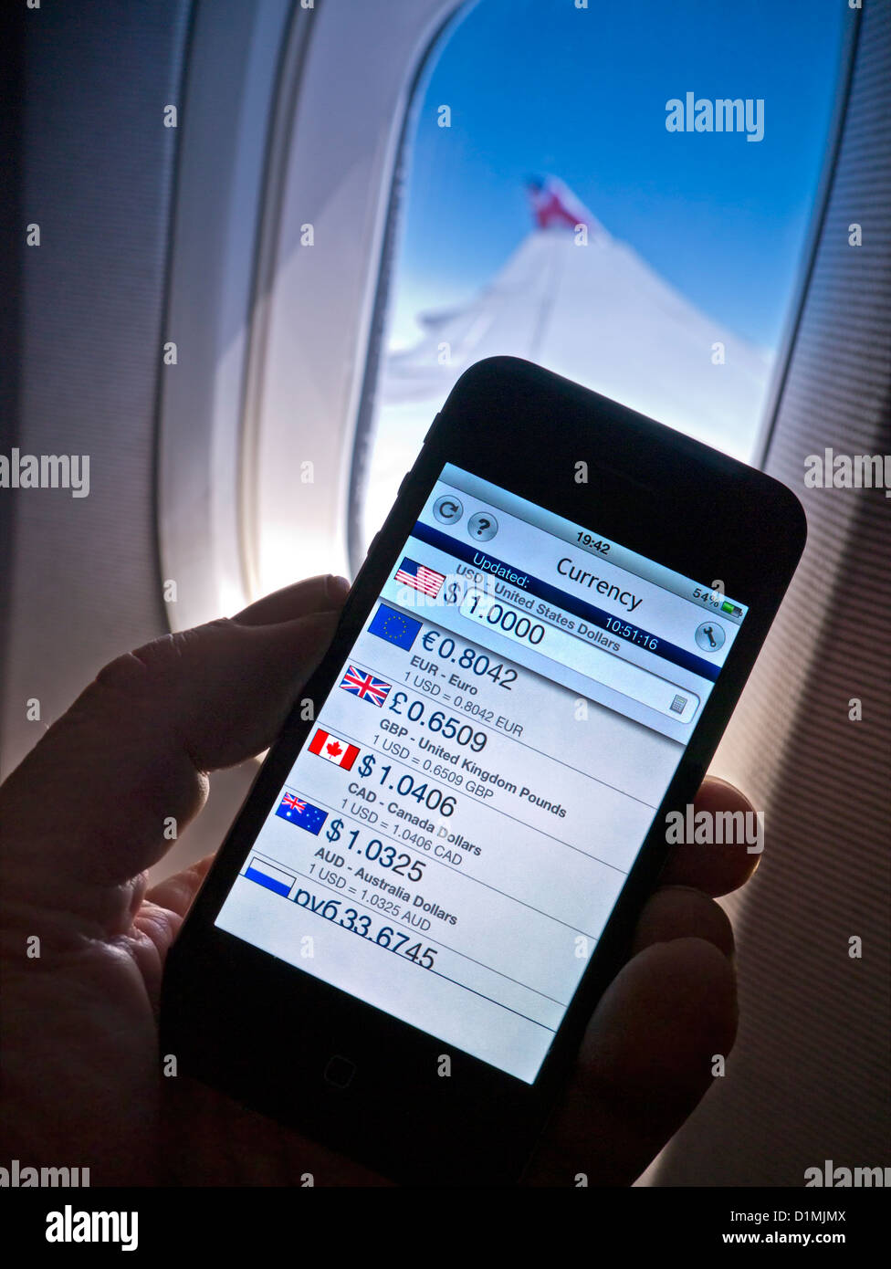 Exchange rates 2012 iPhone 4s smartphone app displaying historic international currency exchange rate in-flight, with cabin window wing and sky behind Stock Photo