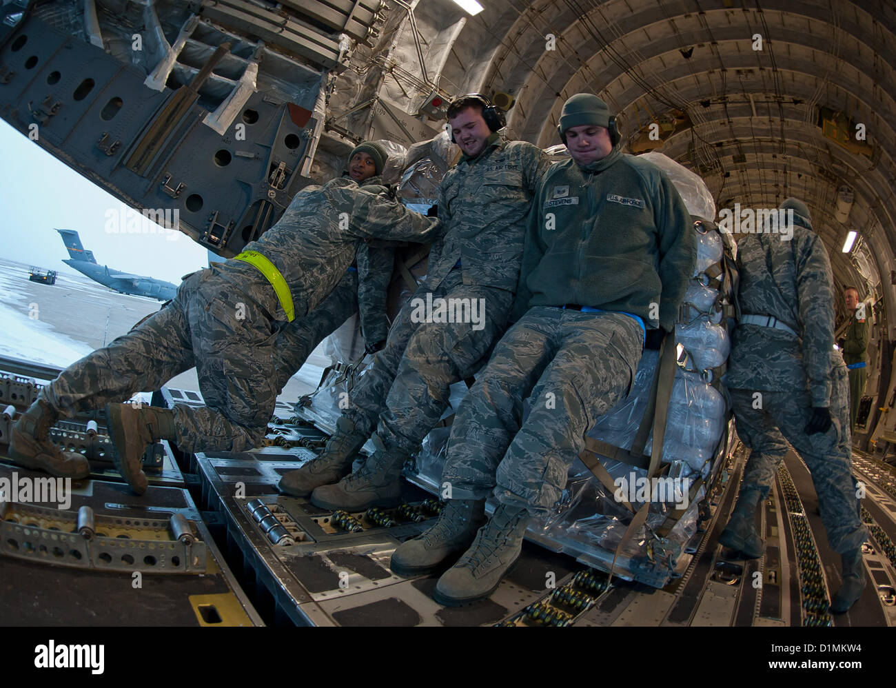 ALTUS AIR FORCE BASE, Okla. – 97th Logistics Readiness Squadron aerial operations flight members push a pallet loaded with food into the back of a C-17 Globemaster III, Dec. 28, 2012. The 58th Airlift Squadron transported the food to Port-au-Prince, Haiti to provide relief by helping feed Haitian children.US Air force Photo Stock Photo