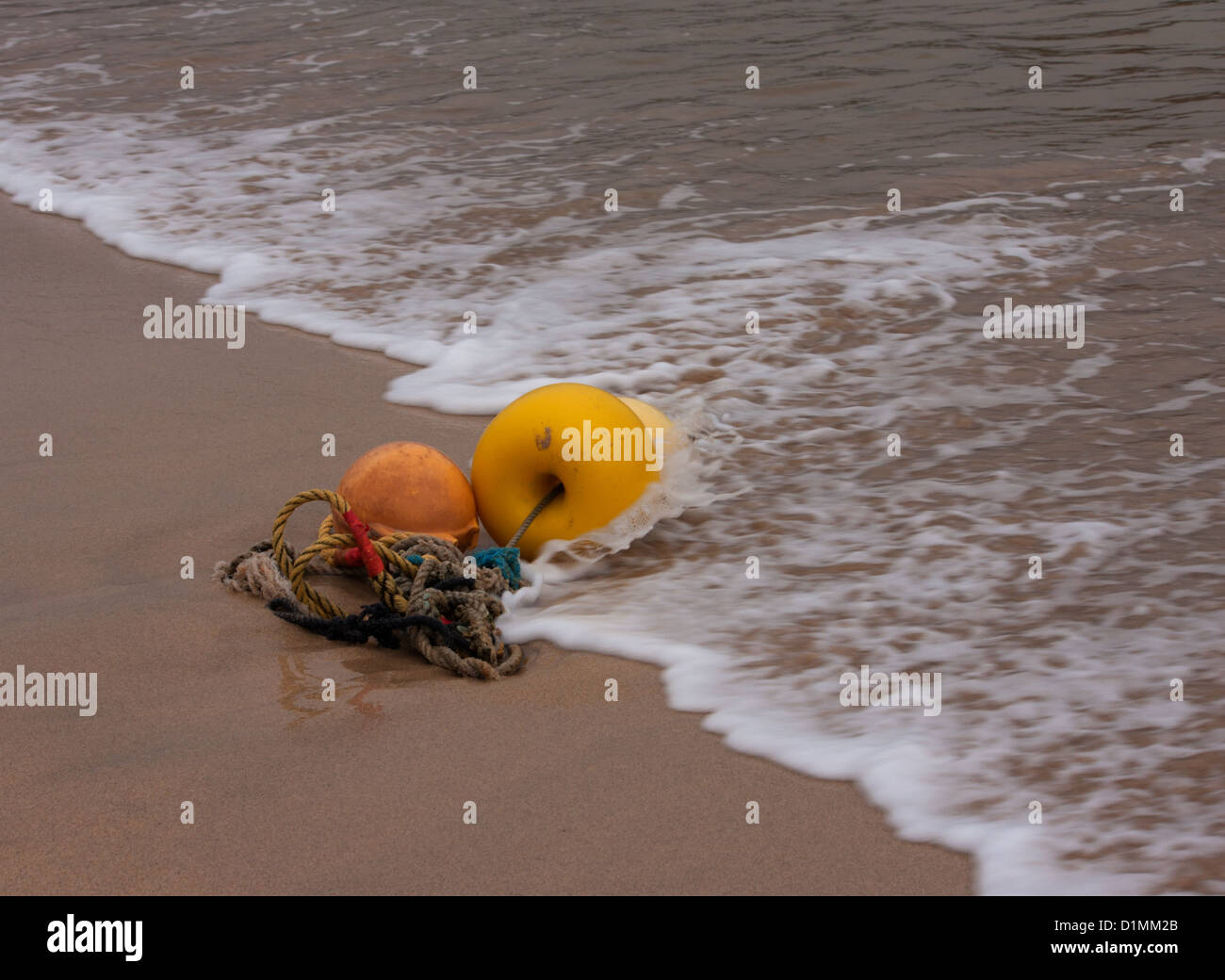 Yellow and orange mooring buoys at the edge of the outgoing tide Stock