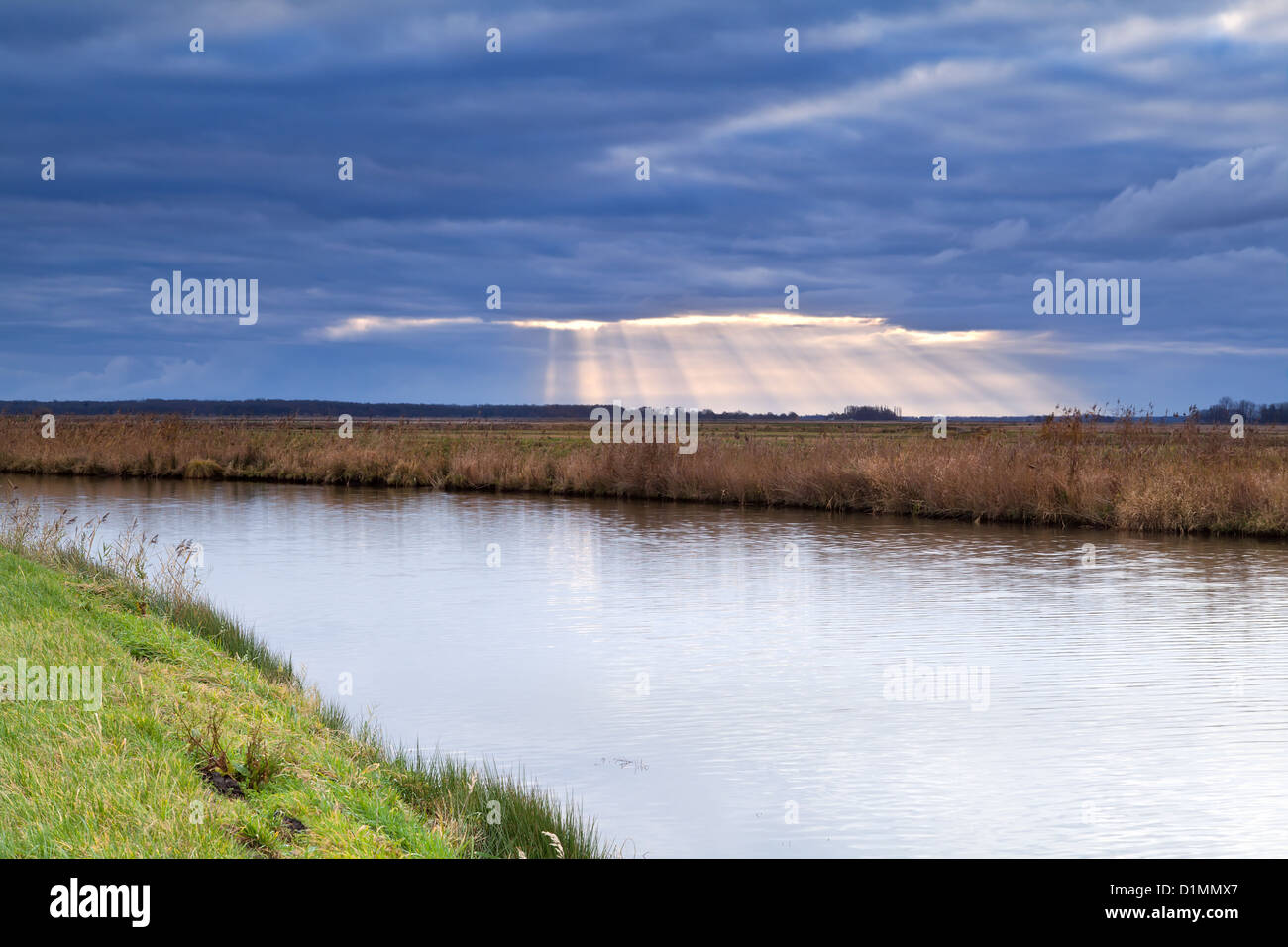 sunbeams through clouded sky during storm over canal Stock Photo