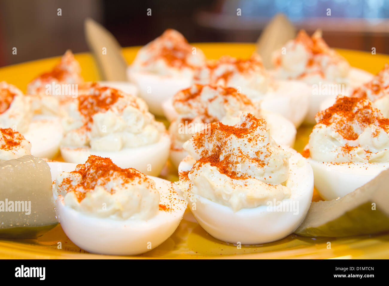 Plate of Deviled Eggs Hors D'Oeuvre sprinkled with Paprika Spice and Pickles Closeup Stock Photo