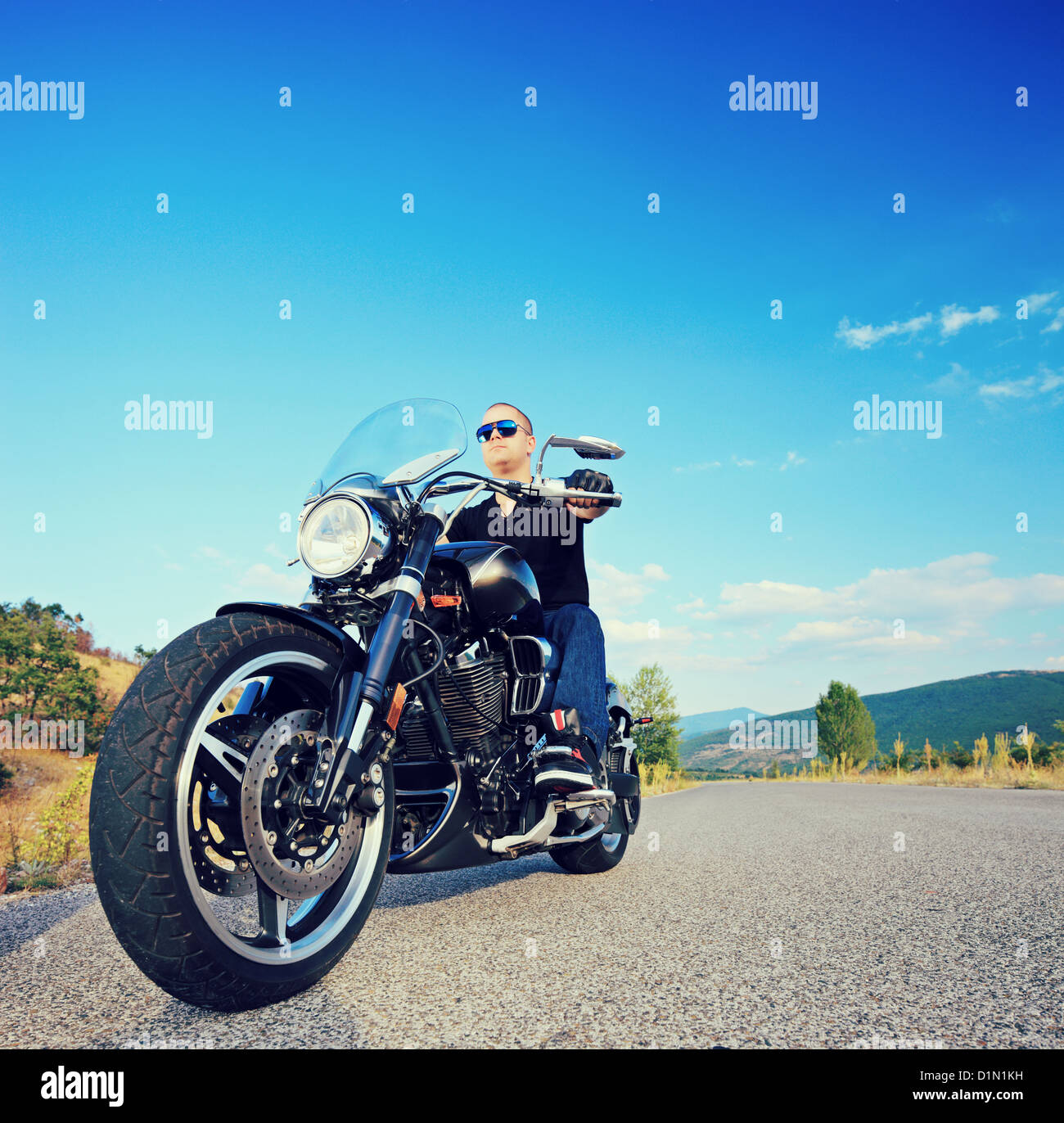 A biker riding a customized motorcycle on an open road, shot with a tilt and shift lens Stock Photo