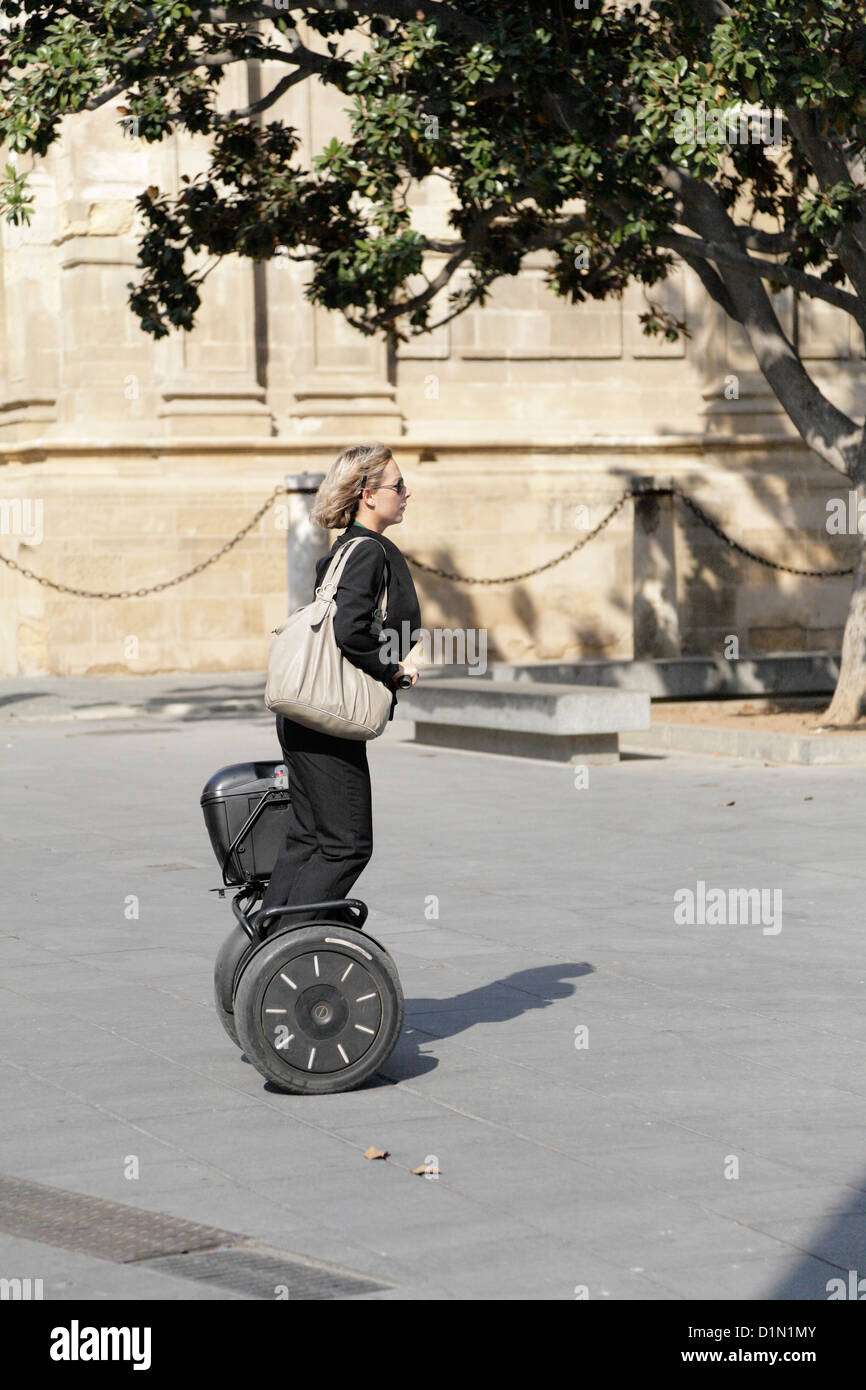 Smart young business woman riding a Segway past Seville Cathedral Spain Stock Photo