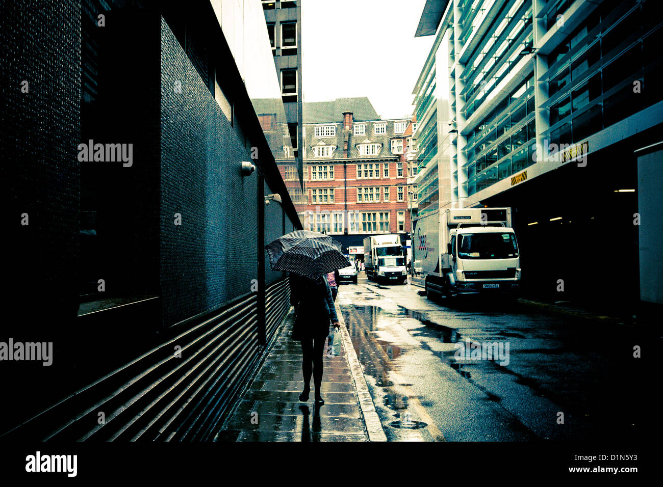 A woman walking in the rain holding an umbrella Stock Photo
