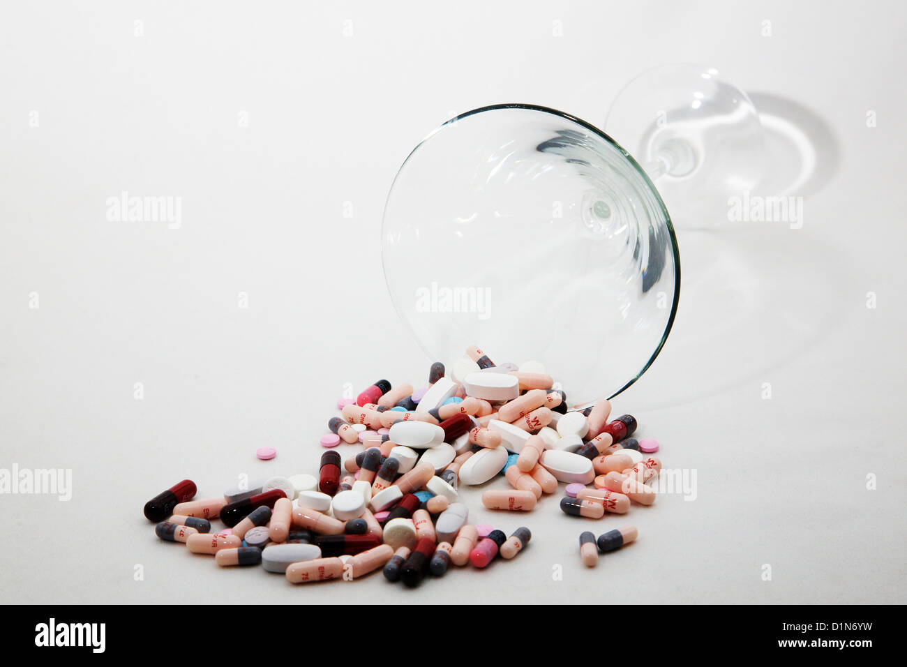 Prescription pills, tablets, capsules spilling from martini glass. White background. Stock Photo