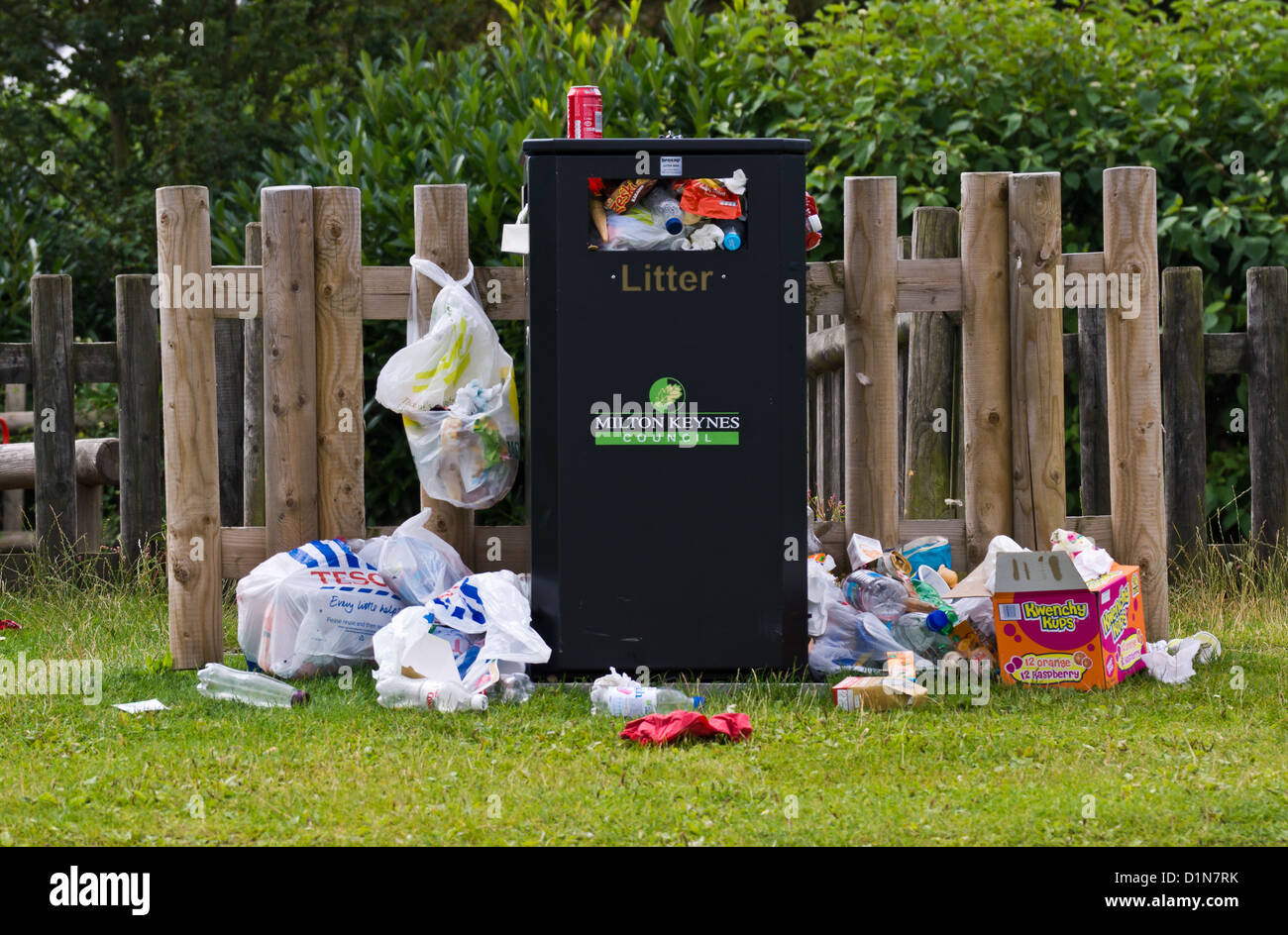 Rubbish overflowing a bin in a park Stock Photo