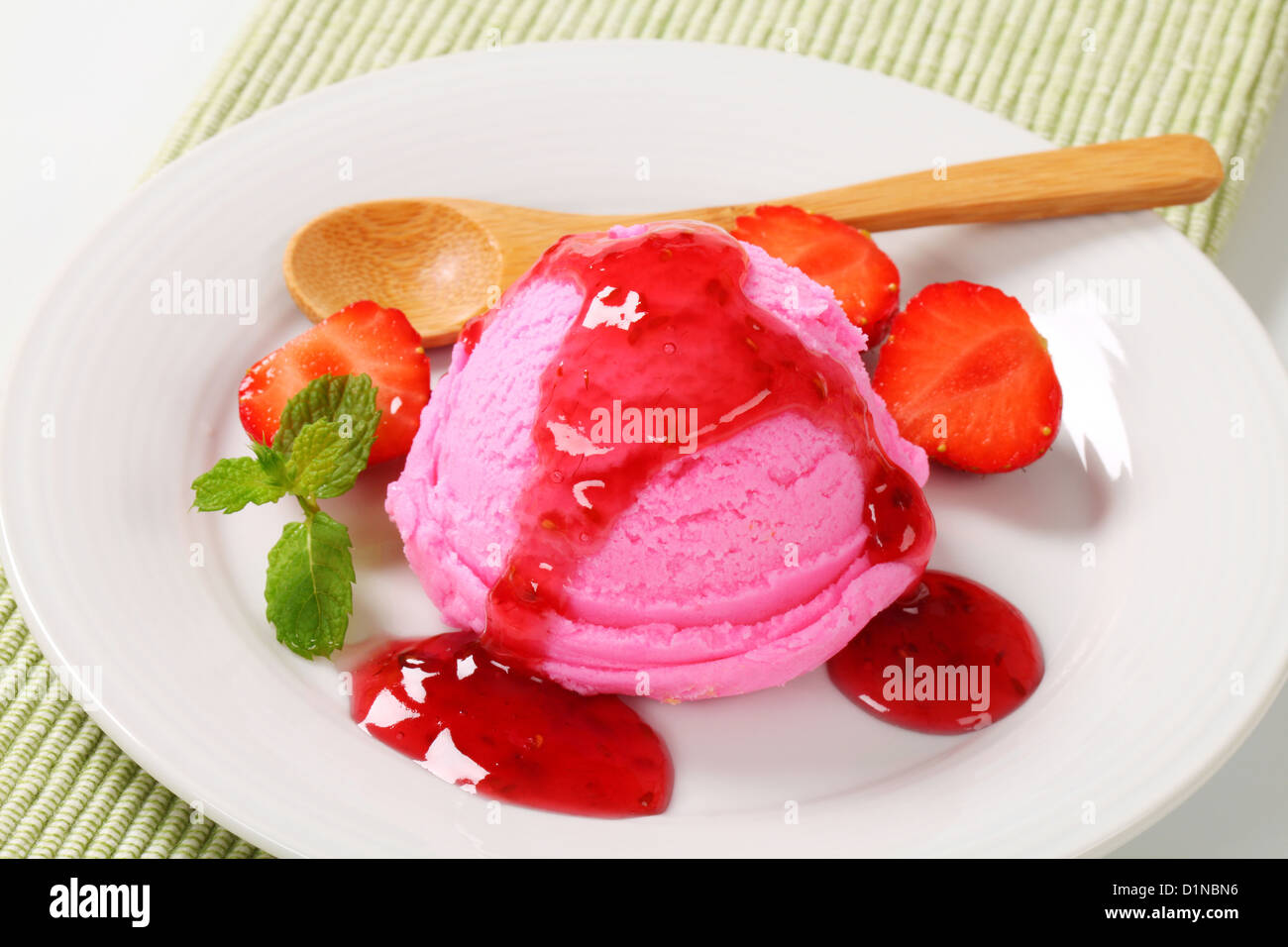 Scoop of pink ice cream with strawberry sauce Stock Photo