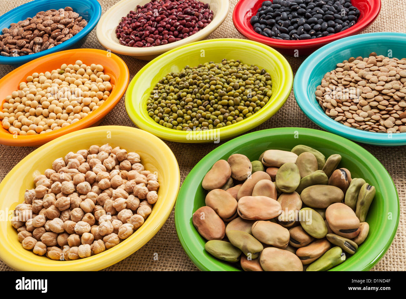 variety of legumes (fava bean, mung bean, soy, green lentils, adzuki, black, pinto, chickpea) in colorful ceramic bowls Stock Photo