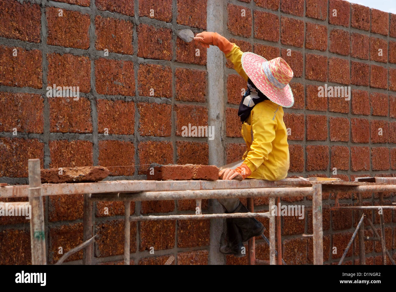 Worker is Constructing large wall with laterite brick. Stock Photo