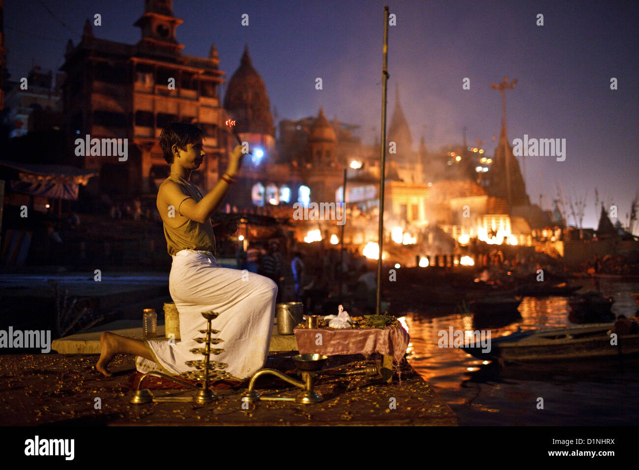 A young brahmin priest performs evening aarti ceremony near the Burning Ghat (Manikarnika Ghat) on the Ganges in Varanasi, India Stock Photo