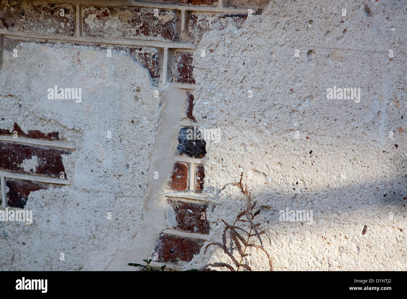 Brick wall with plaster on top, and the plaster is cracked and breaking