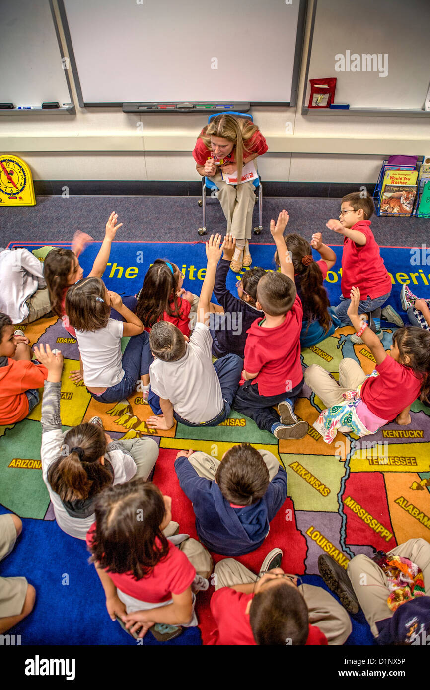 A volunteer teacher sponsored by her employer reads to Hispanic elementary schoolchildren in Santa Ana, CA. Stock Photo