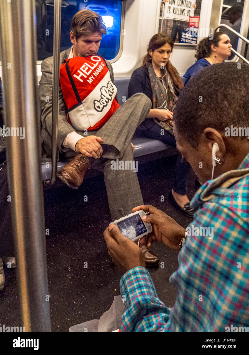 An African American man plays a video game on a Smartphone while riding in the New York City subway. Stock Photo