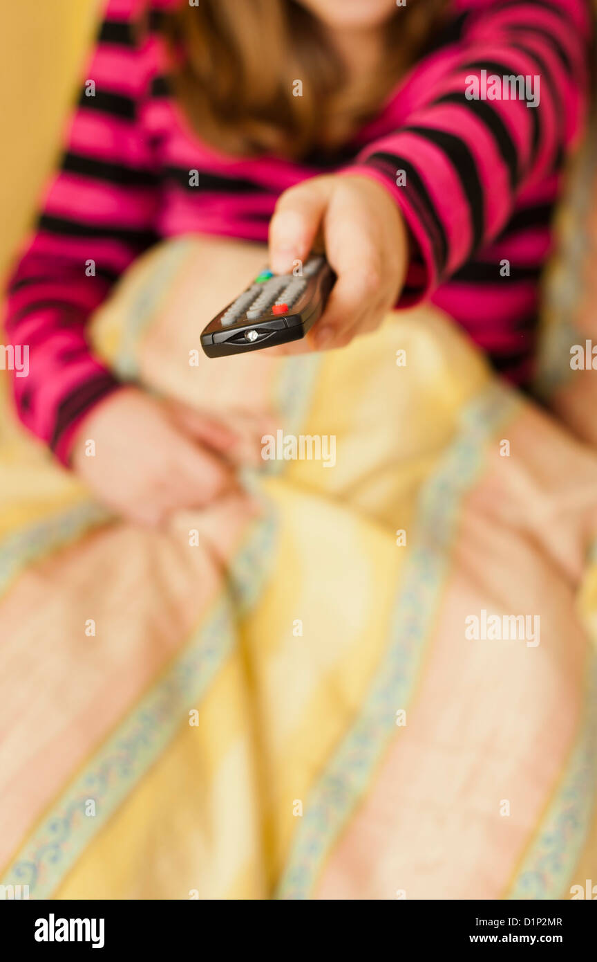girl in bed holding a television remote control Stock Photo