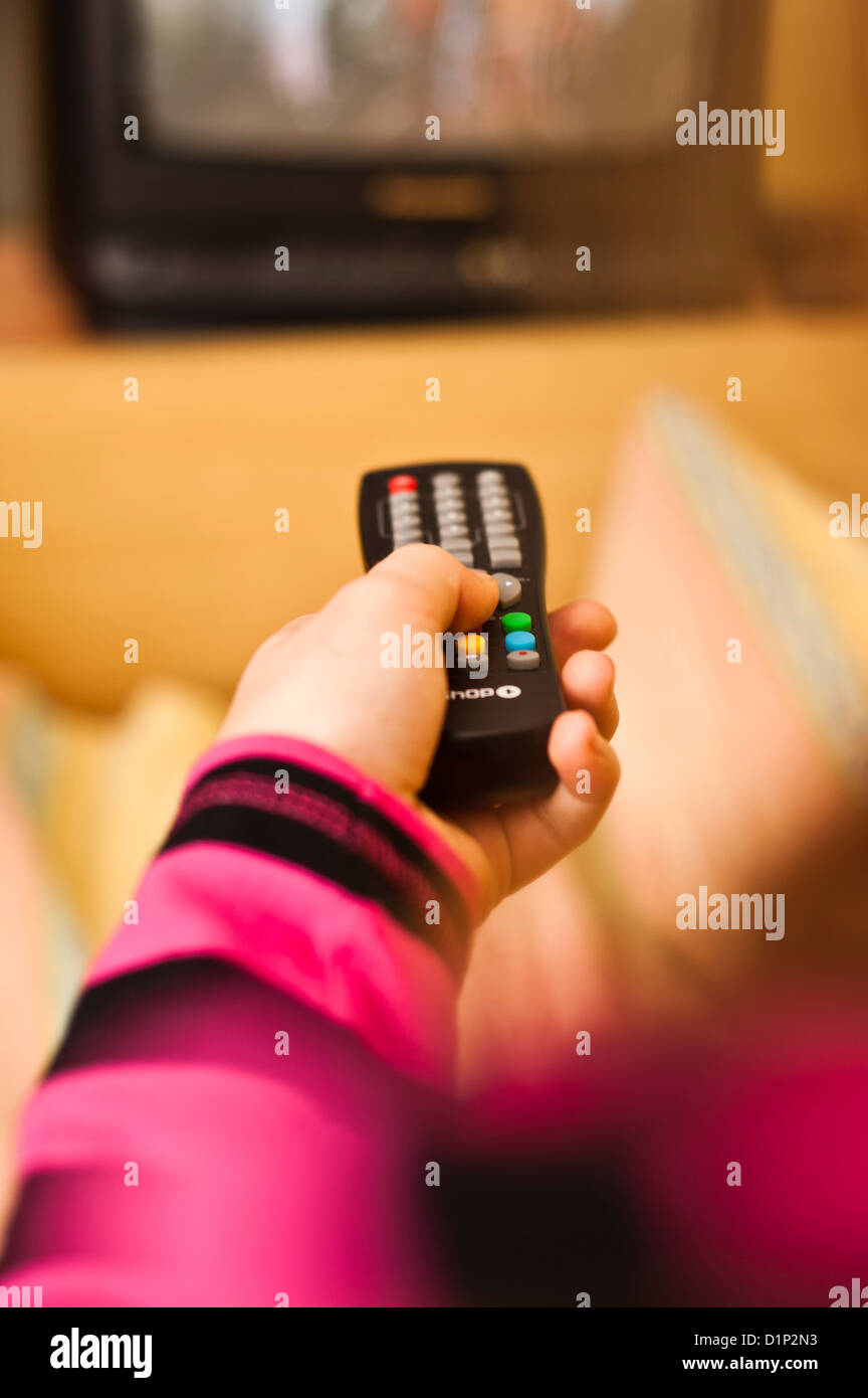 girl in bed holding a television remote control Stock Photo