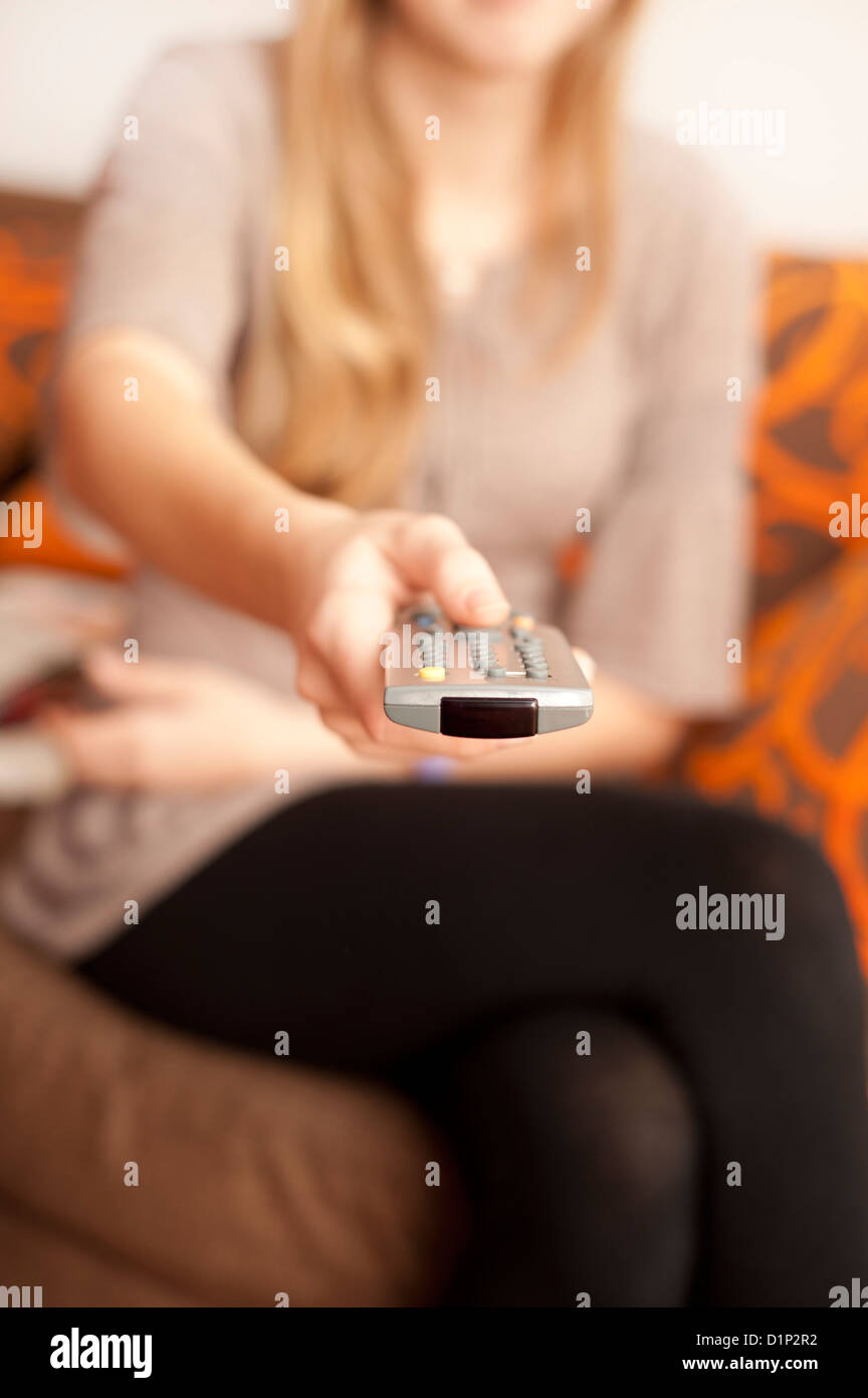 woman holding and pointing a TV remote Stock Photo