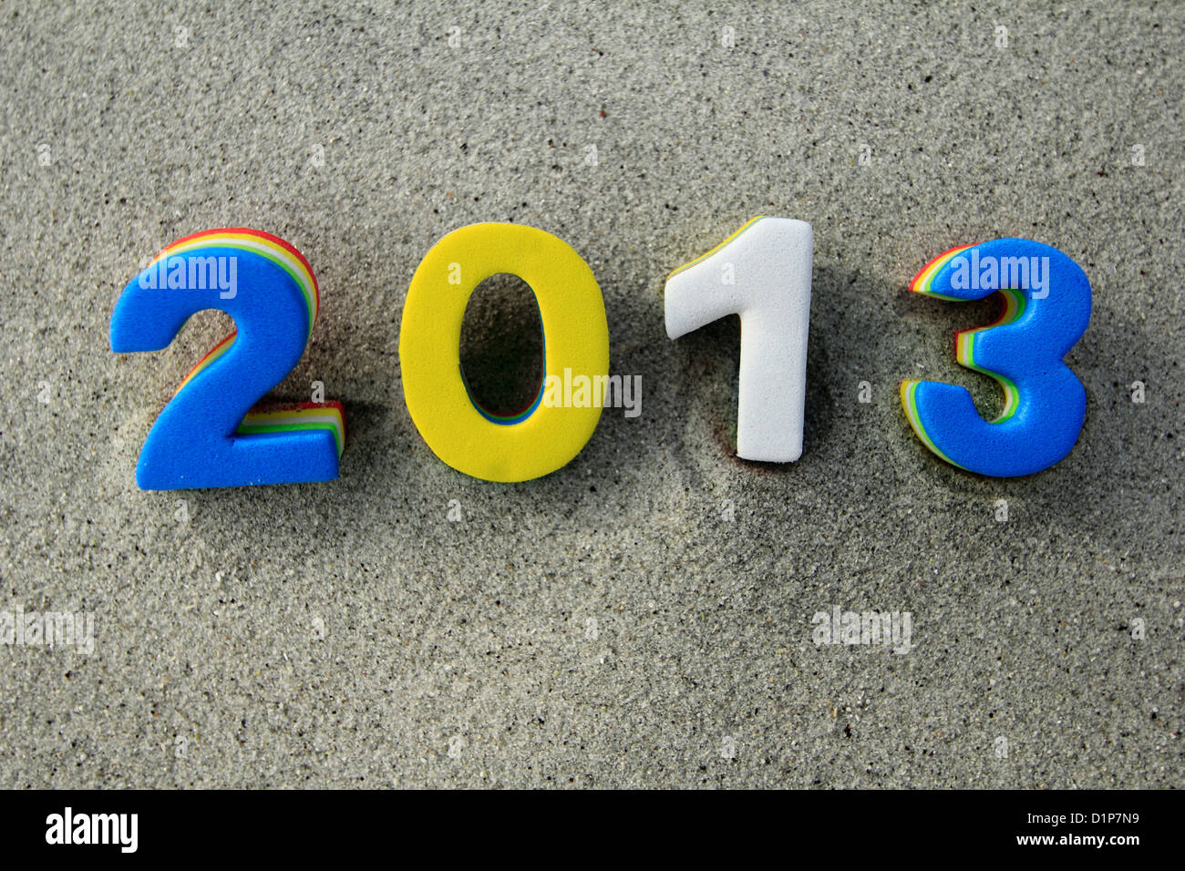 The year 2012 two thousand and thirteen in blue yellow and white numbers on a background of beach sand Stock Photo