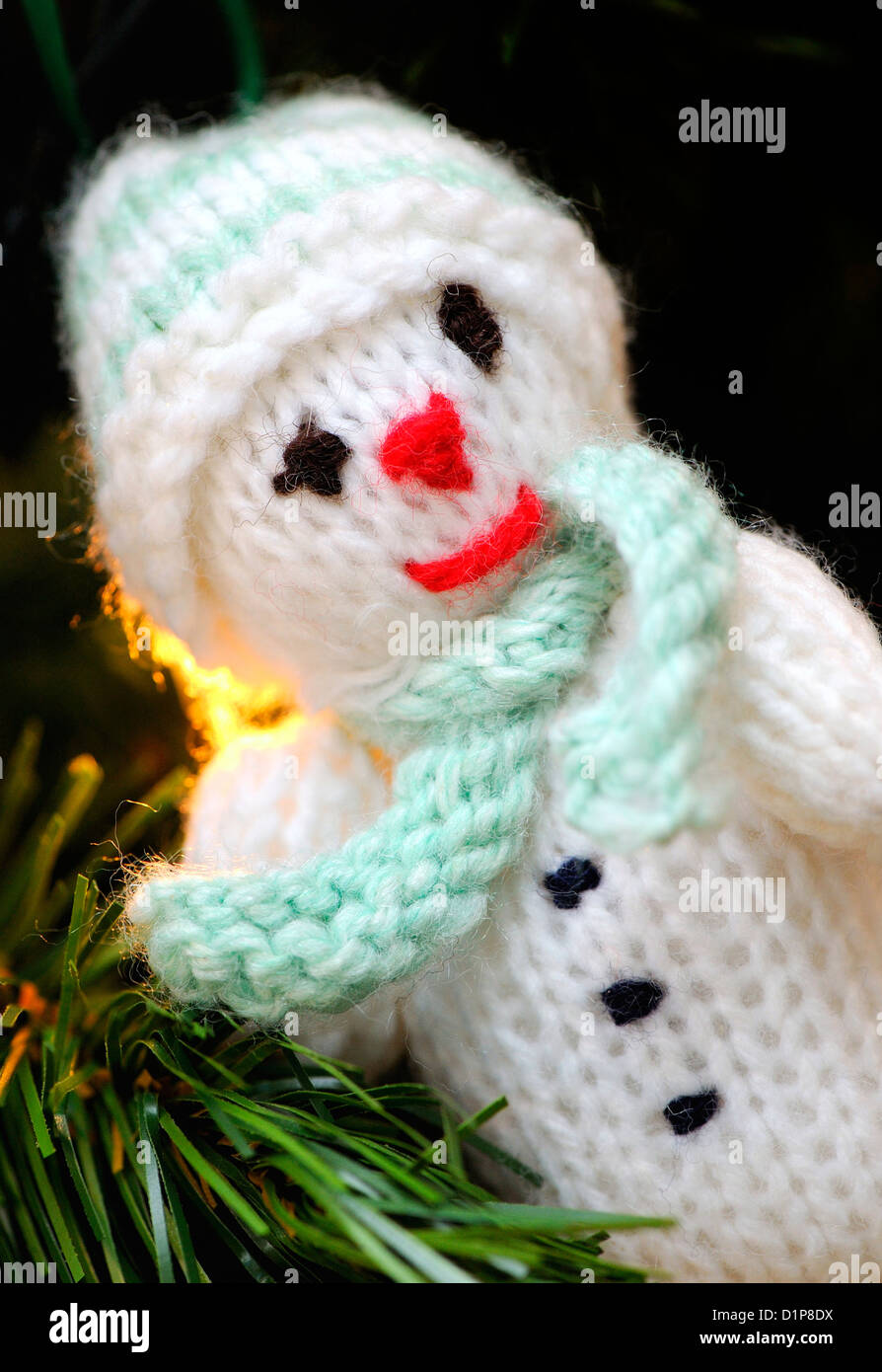 White knitted snowman with a light green scarf and hat used as a Christmas decoration. Stock Photo