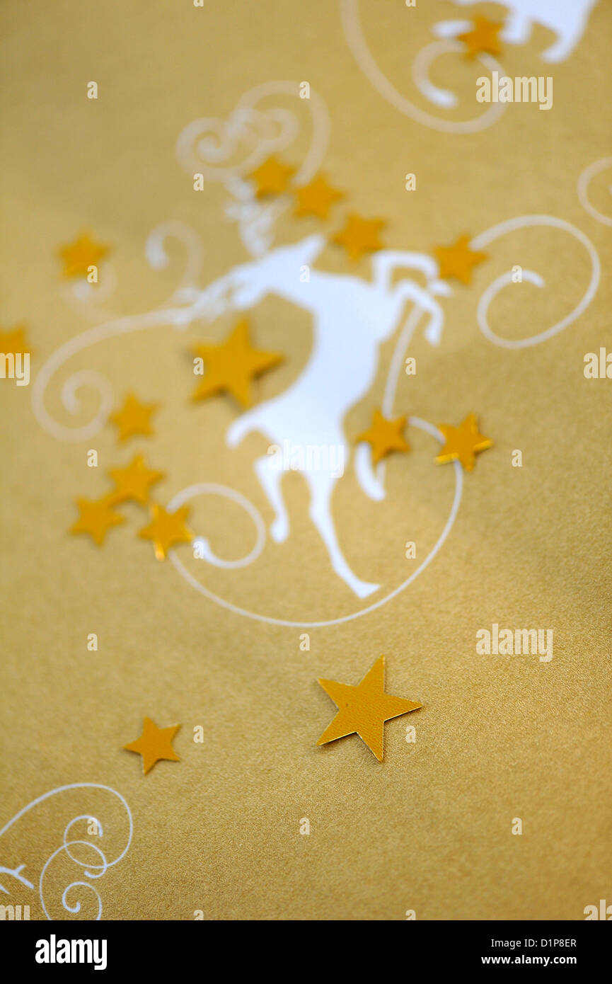Gold coloured Christmas wrapping paper with a print of a white deer and gold coloured stars Stock Photo