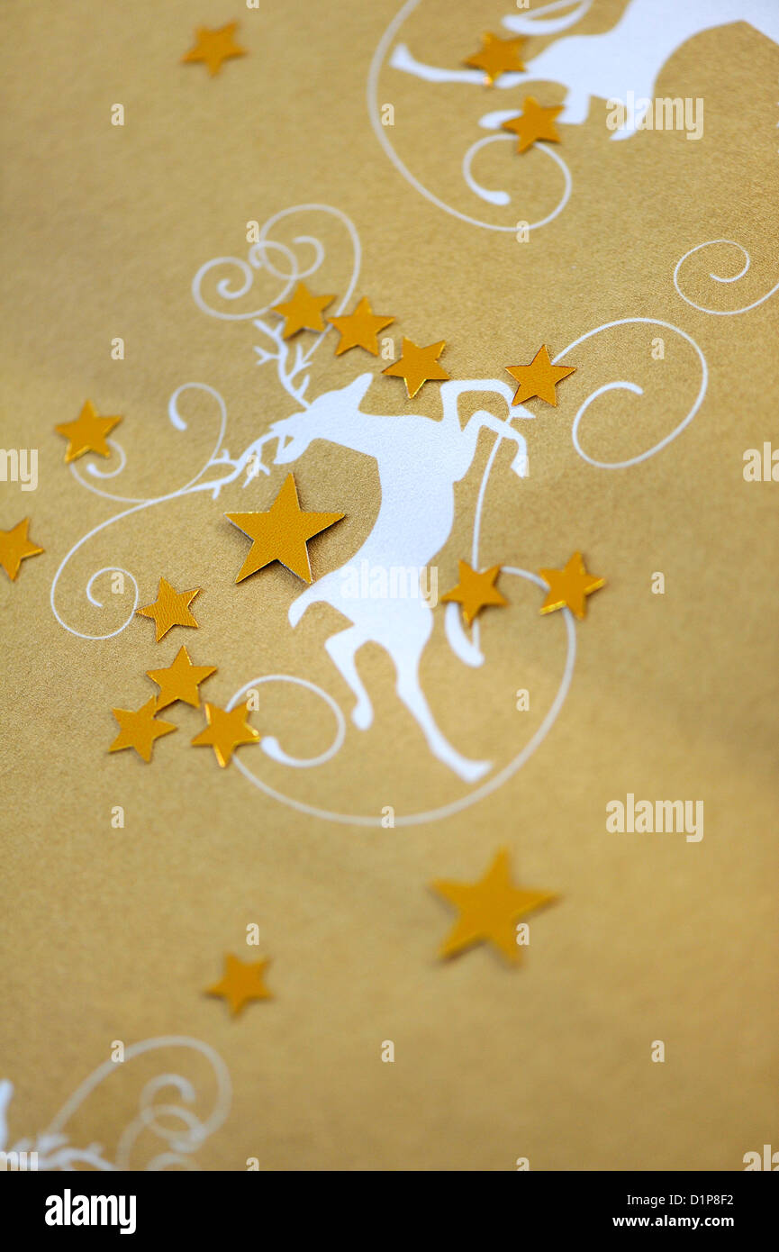 Gold coloured Christmas wrapping paper with a print of a white deer and gold coloured stars Stock Photo