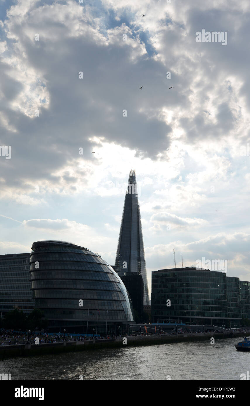 The Shard building in London behind the Thames side City Hall, back lit under brooding skies Stock Photo