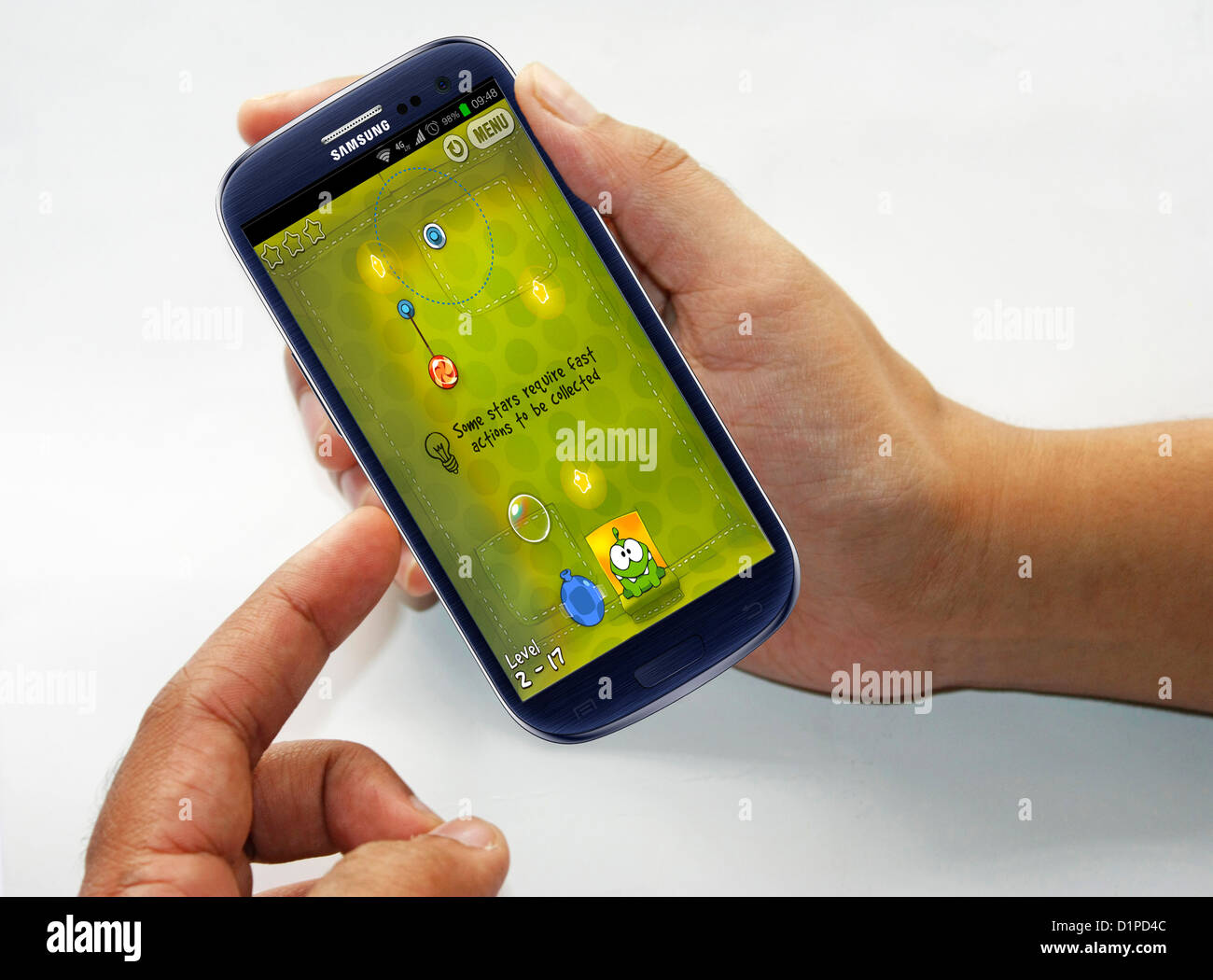A person playing a game of Cut the rope in android mobile Stock Photo