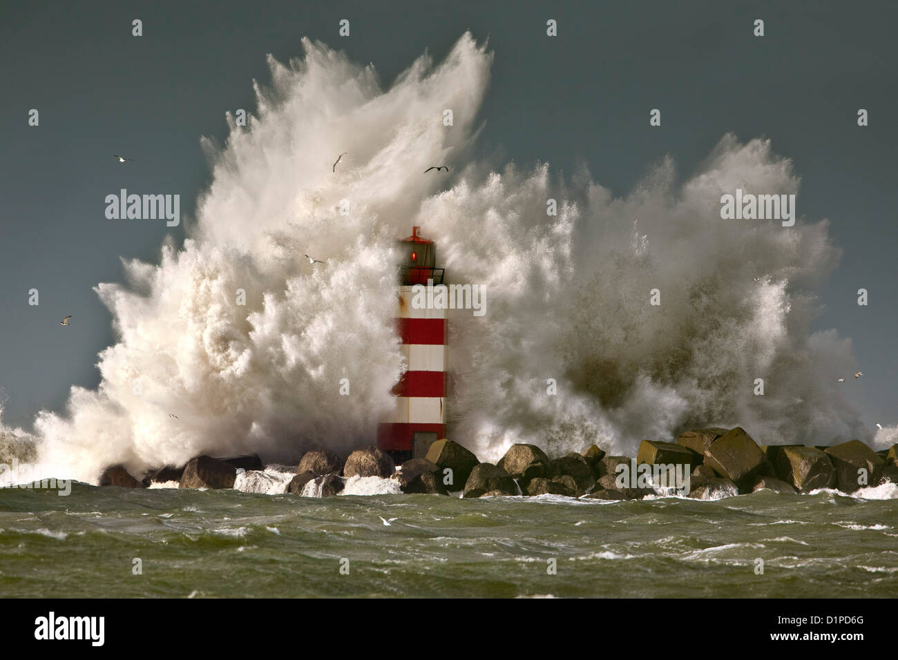 The Netherlands, IJmuiden, Storm. Waves crash against lighthouse or beacon. Stock Photo