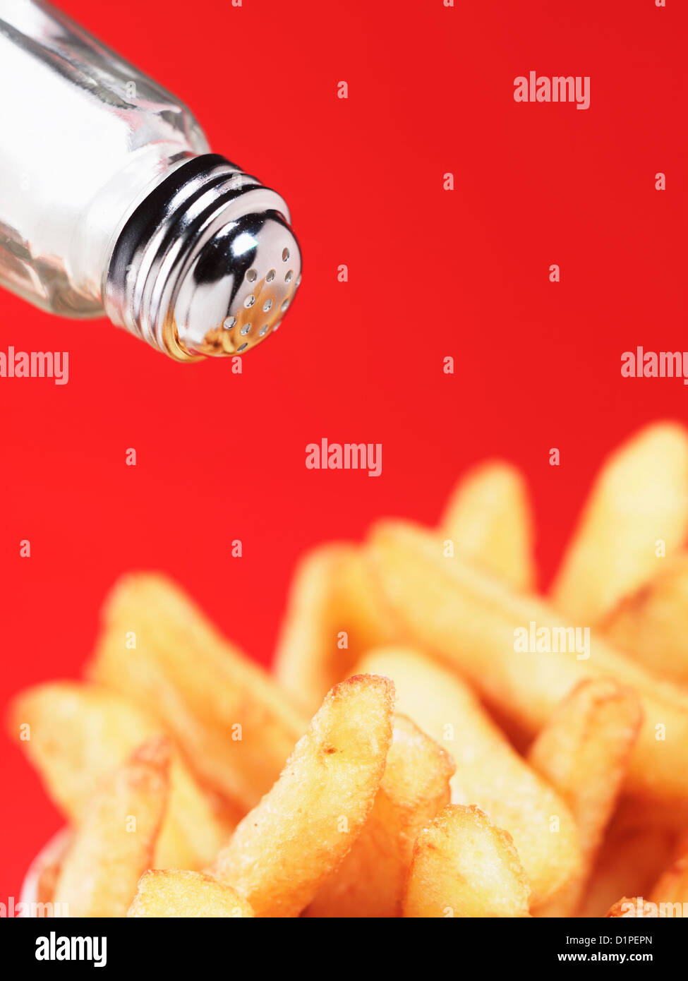 sprinkling salt on chips against red background Stock Photo Alamy