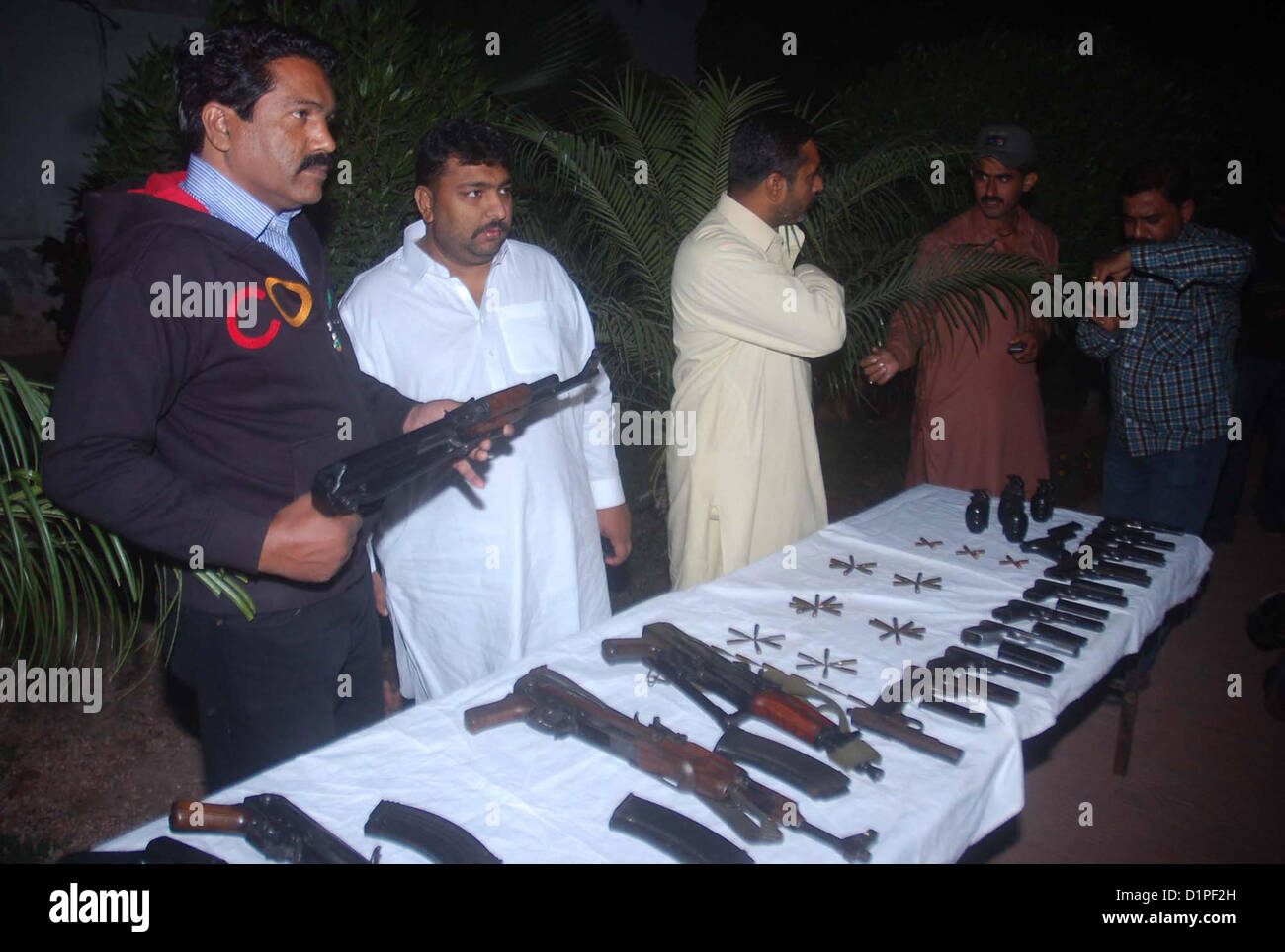 CID Police Officials show seized weapon to media persons  that recovered from activists of defunct organizations during targeted raids in different areas, at  Garden Police Headquarter in Karachi on Wednesday, January 02, 2013. These arrestees were in  involved in sectarian target killing. CID officials recovered 02 Kalashnikov, 05 Hand Grenade,  11 Pistols, 02 Tripple-2 Riffles, 01 Repeater Riffles and different types of bullets. Stock Photo