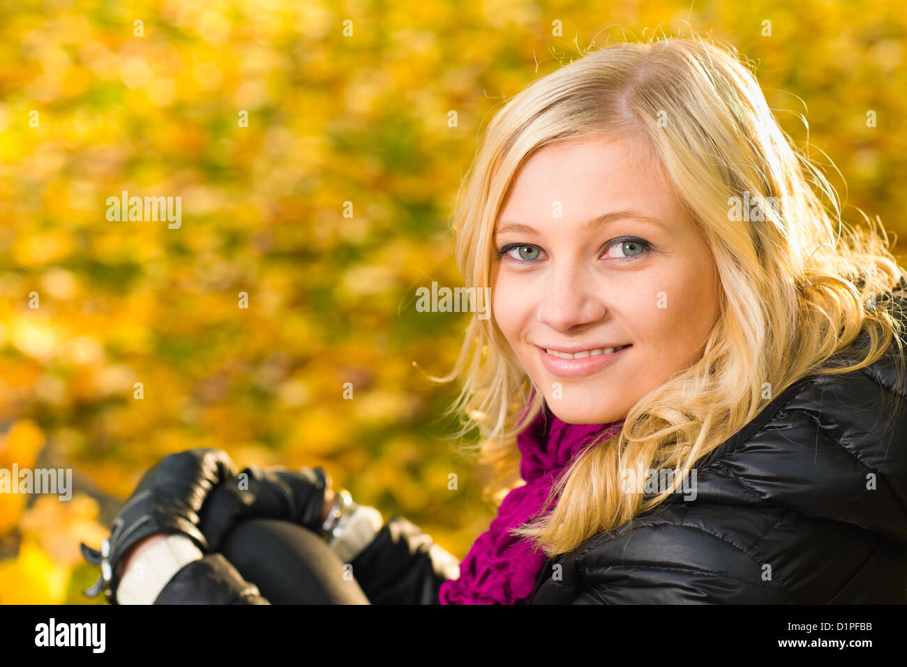 Beautiful girl sitting, autumn color leaves on the background, horizon format Stock Photo