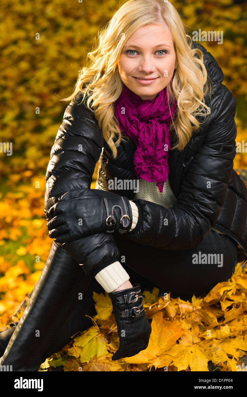 Beautiful girl sitting, autumn color leaves on the background, vertical format Stock Photo