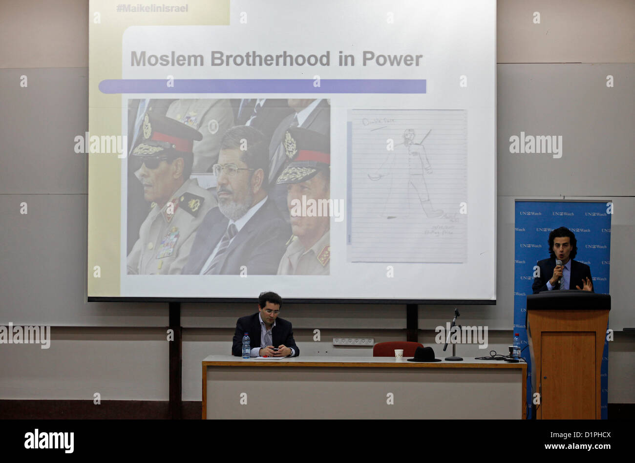 Maikel Nabil Sanad, an Egyptian blogger and political activist speaks next to an image showing the Egyptian PM Mohamed Morsi sitting with other military generals during a speech in Tel Aviv University on 02 January 2012. Maikel became famous in 2010 for refusing to serve in the Egyptian army, then in 2011 for his role in the Egyptian revolution. He is known for promoting liberal democratic values in Egypt, and campaigning for peaceful relations between Egypt and Israel. Stock Photo