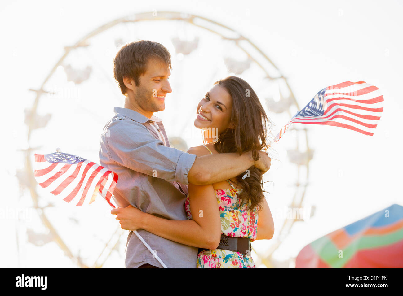 Caucasian couple holding American flags and enjoying carnival Stock