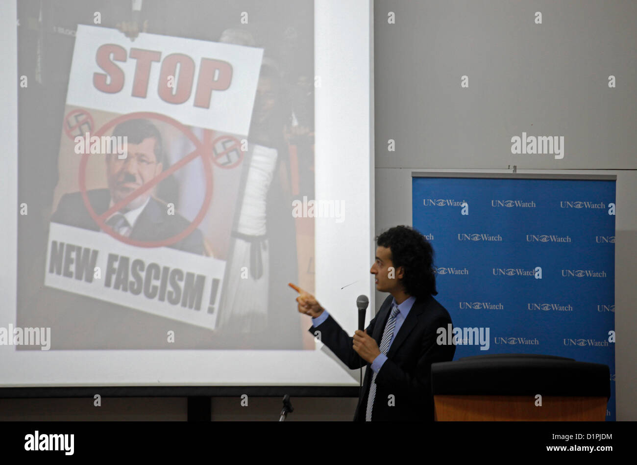 Maikel Nabil Sanad, an Egyptian blogger and political activist points at an image screened depicting Egyptian PM Mohamed Morsi with writing 'Stop, New Fascism' during a speech in Tel Aviv University on 02 January 2012. Maikel became famous in 2010 for refusing to serve in the Egyptian army, then in 2011 for his role in the Egyptian revolution. He is known for promoting liberal democratic values in Egypt, and campaigning for peaceful relations between Egypt and Israel. Stock Photo