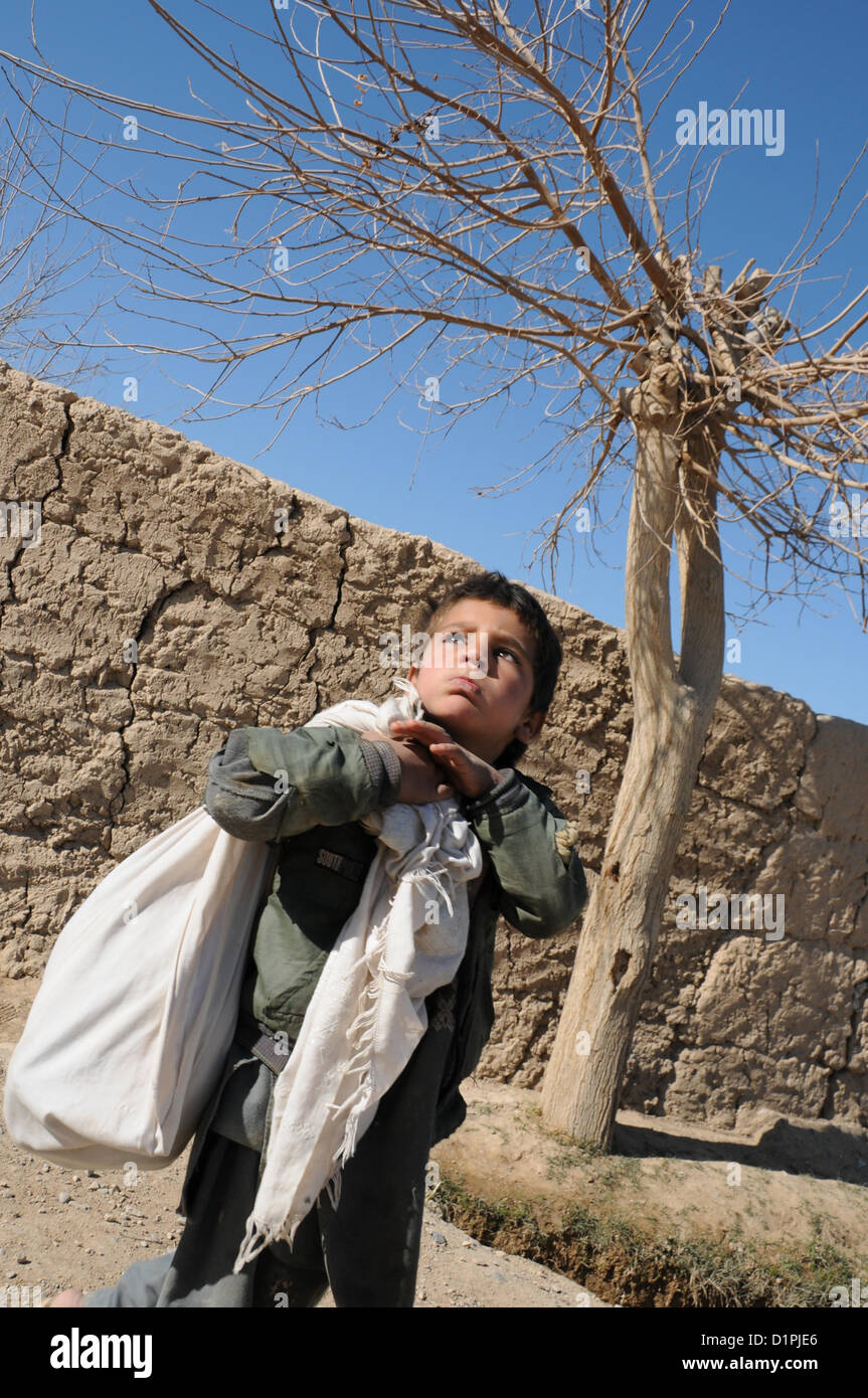 An Afghan boy carries a load of goods slung over his shoulder in Bala Boluk, Jan. 2.  PRT Farah's mission is to train, advise, and assist Afghan government leaders at the municipal, district, and provincial levels in Farah province, Afghanistan.  Their civil military team is comprised of members of the U.S. Navy, U.S. Army, the U.S. Department of State and the U.S. Agency for International Development (USAID).  (U.S. Navy photo by Lt. j.g. Matthew Stroup/released) Stock Photo