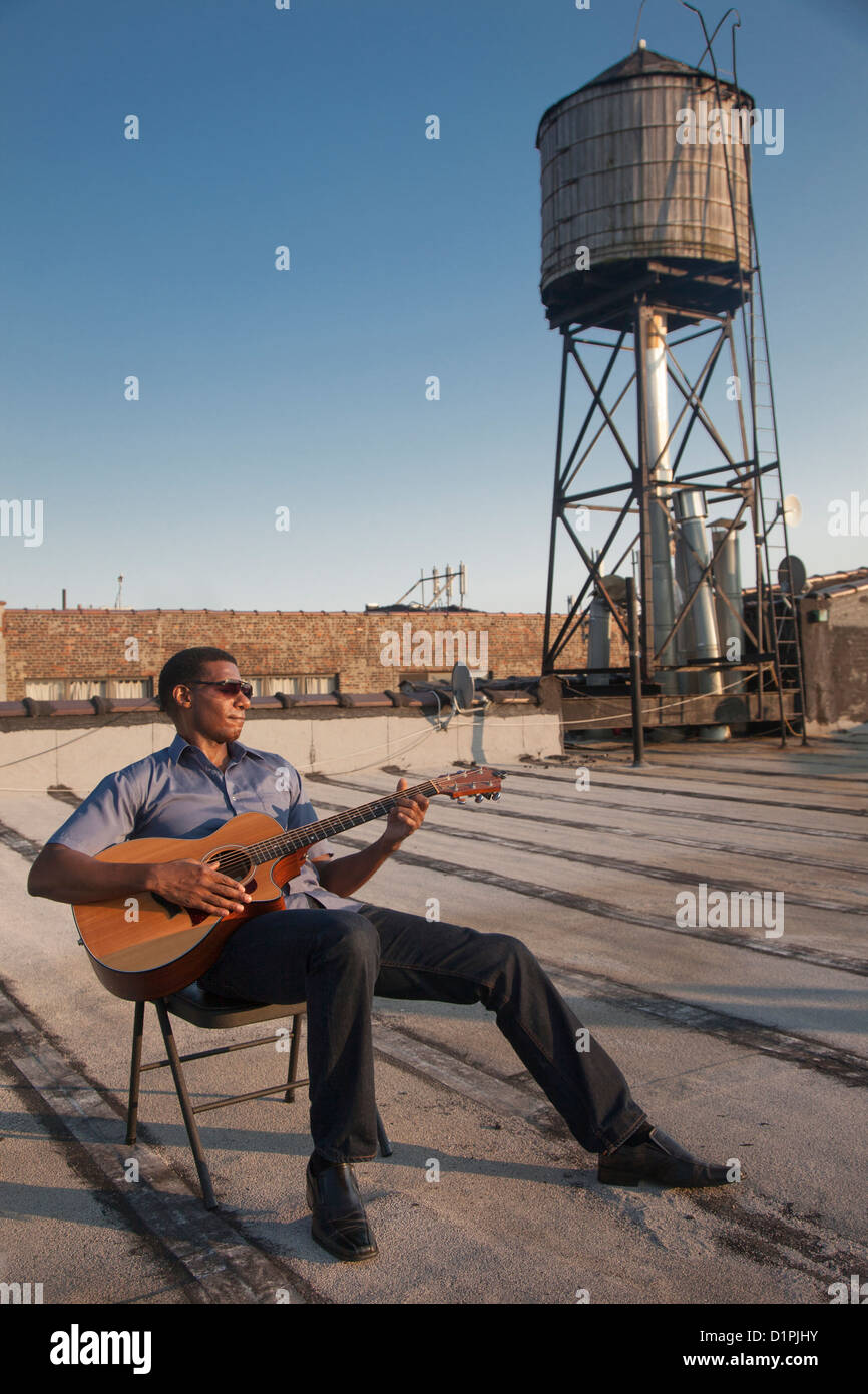 Black man playing guitar on rooftop Stock Photo - Alamy
