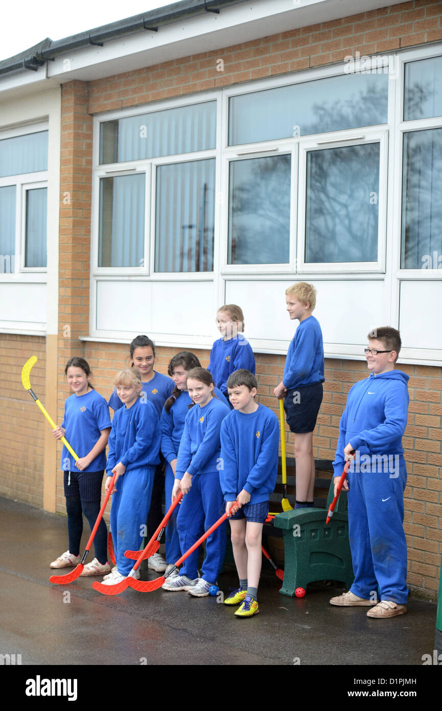 Schoolchildren wait for the rain to stop before starting hockey practice at Our Lady & St. Werburgh's Catholic Primary School in Stock Photo