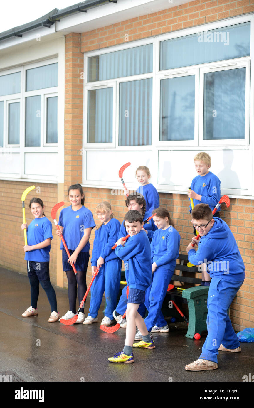 Schoolchildren wait for the rain to stop before starting hockey practice at Our Lady & St. Werburgh's Catholic Primary School in Stock Photo